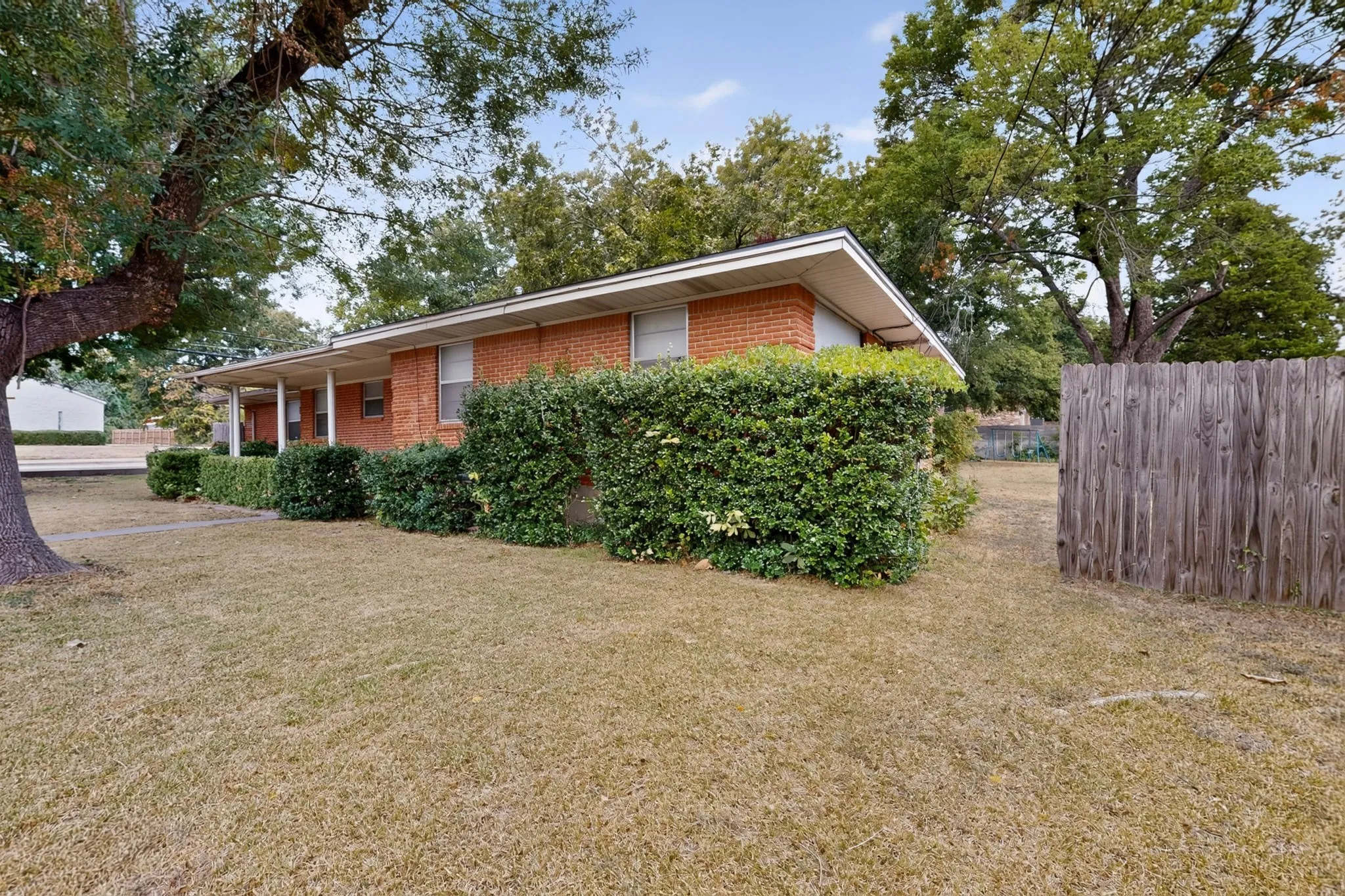 Brick exterior, covered front porch, established landscaping, and a wooden privacy fence