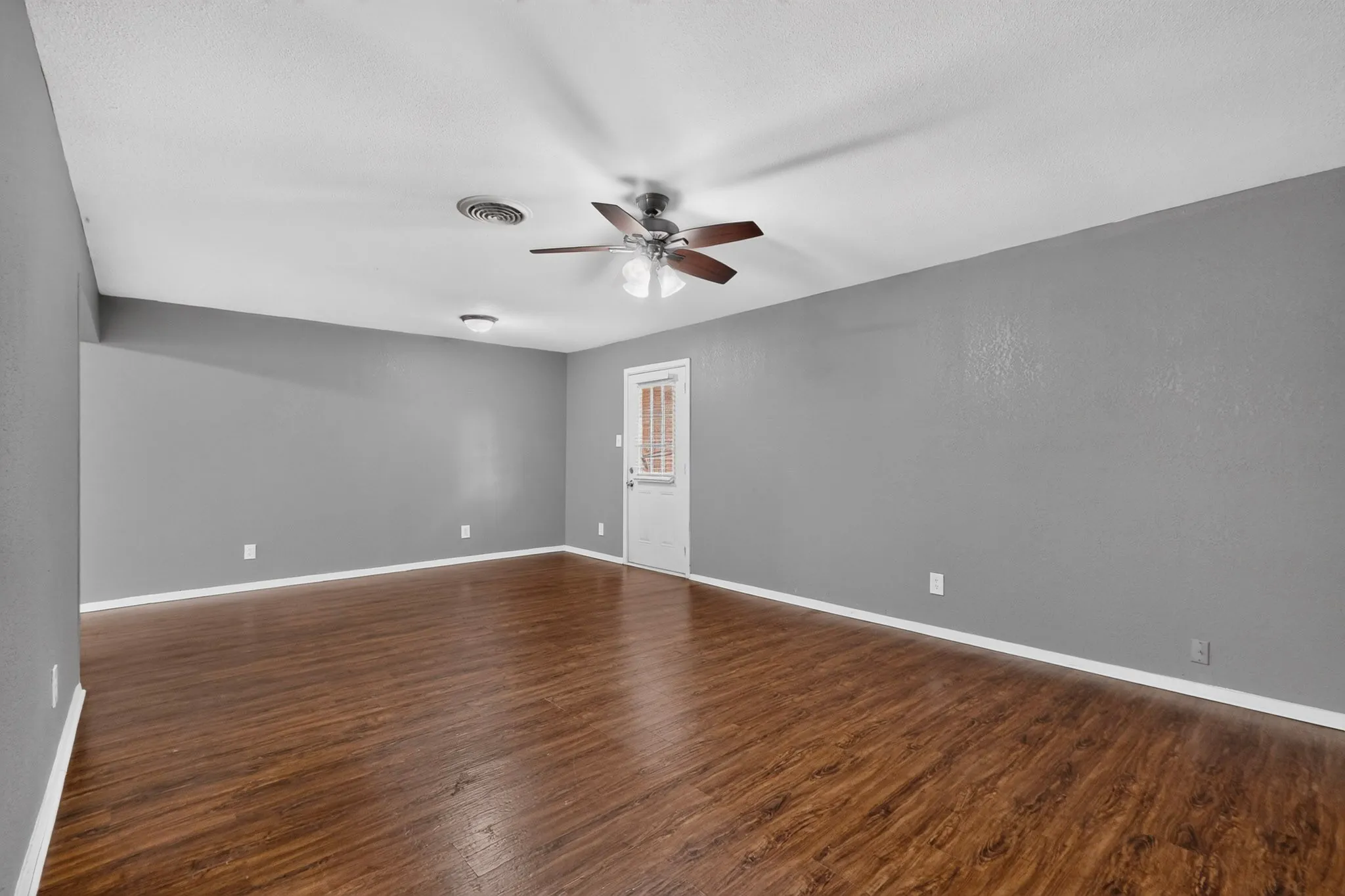 Spacious room with wood-finish flooring, light gray walls, and a white ceiling