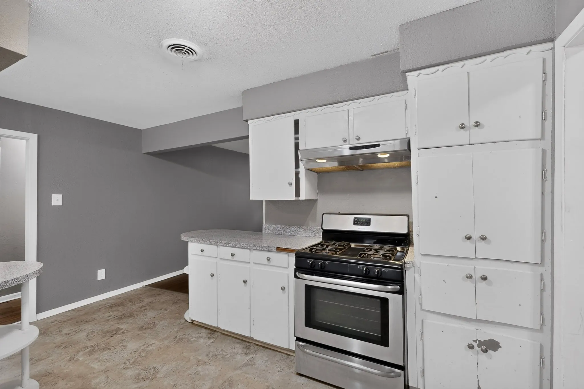 Kitchen featuring white cabinetry with ample storage, stainless steel gas range with convection oven, and tile flooring throughout the space