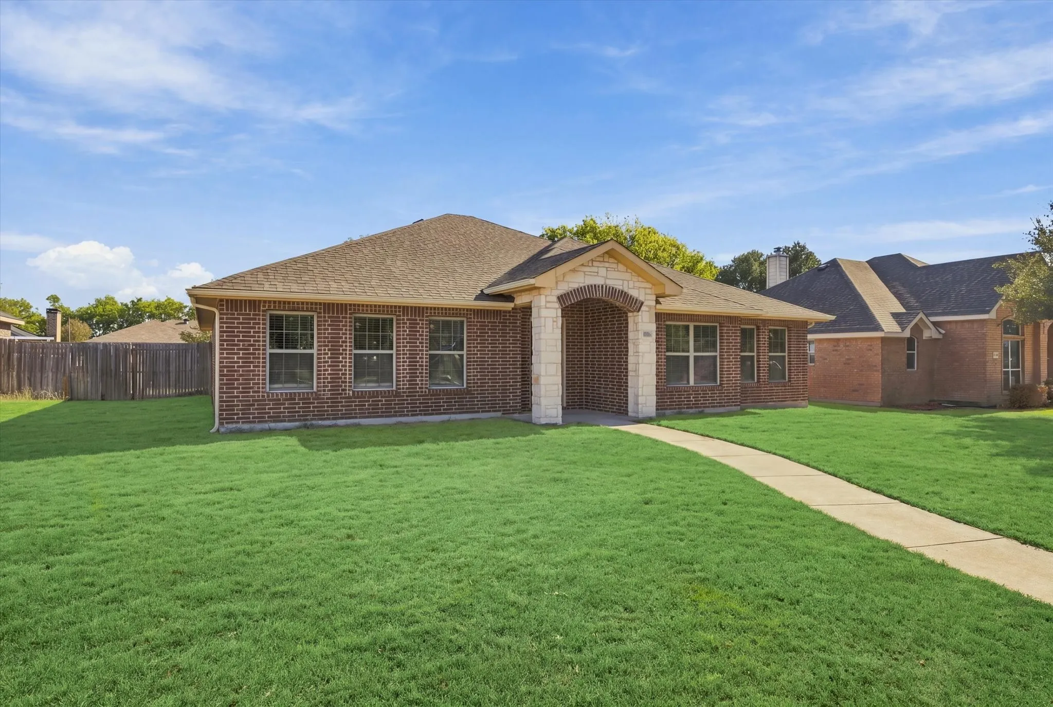 Brick exterior with stone accents, a gabled roof, and a concrete pathway