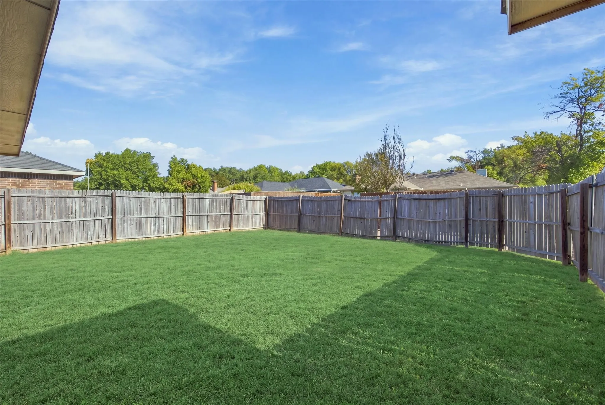 Expansive green lawn with a full perimeter wood fence