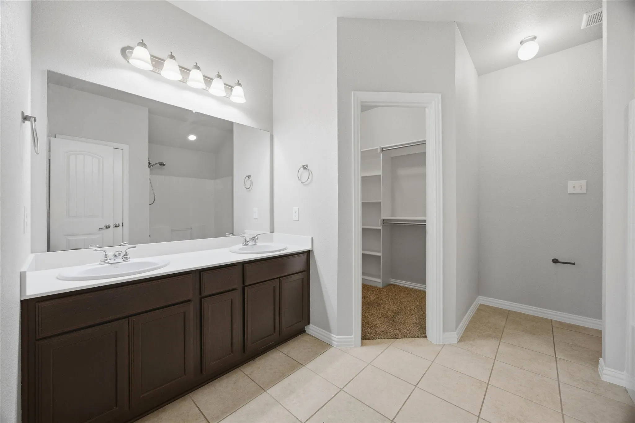 Dual vanity with white countertops, integrated sinks, and brown cabinetry