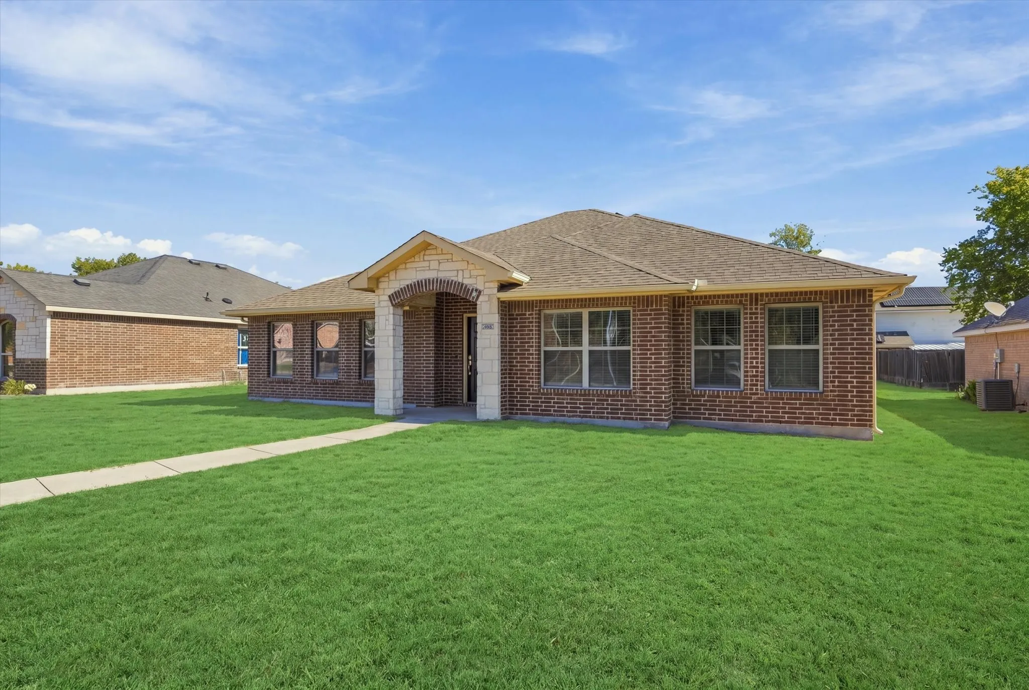 Brick exterior with stone accents, covered entry, multiple windows, and a paved walkway