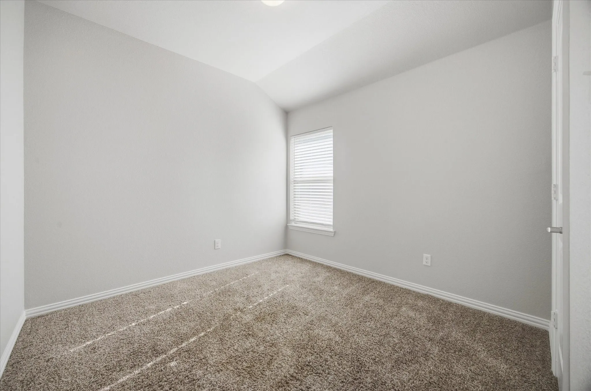 Neutral-toned carpeting, white window blinds, and light gray wall paint