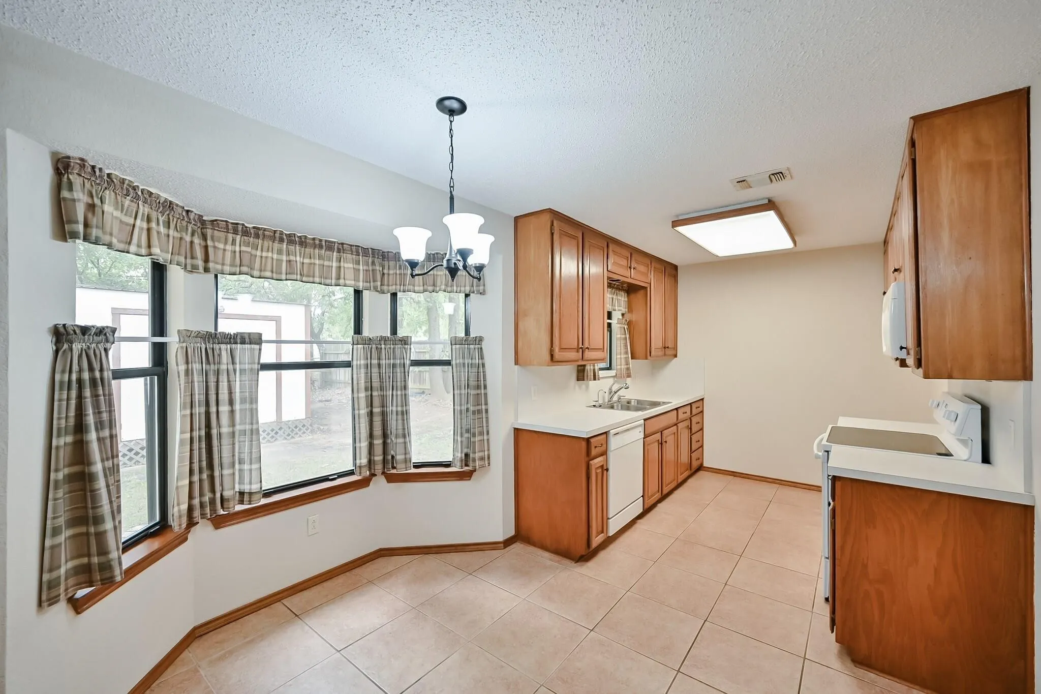 Kitchen with wood cabinetry, light countertops, and tile flooring
