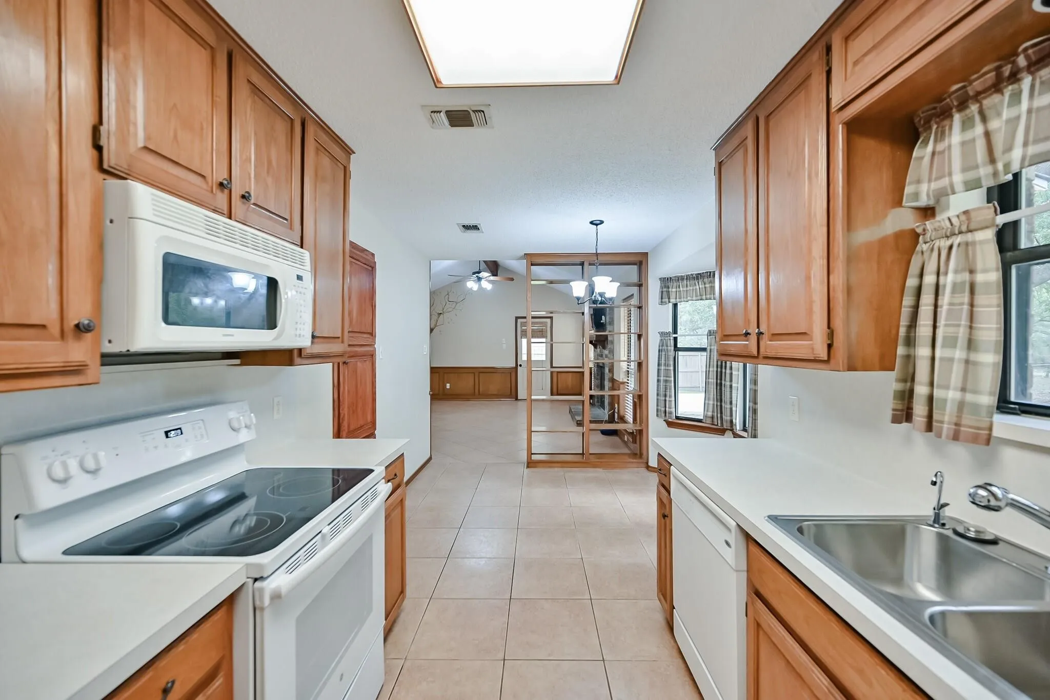 Kitchen featuring wood cabinetry, solid surface countertops, a stainless steel sink, and tile flooring