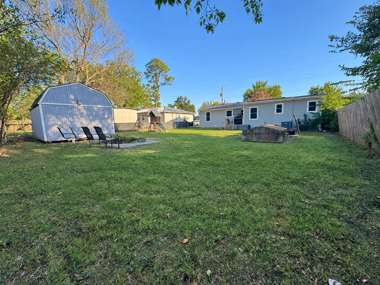 Expansive backyard featuring a manicured lawn, a detached storage shed, a paved patio, and a privacy fence