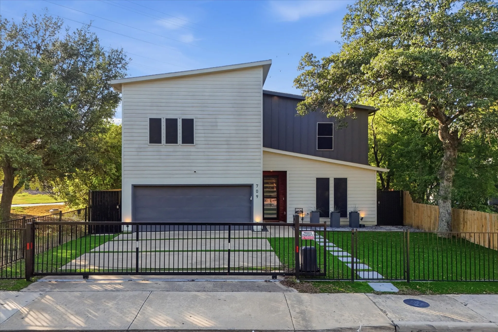 Modern architectural design featuring multi-toned siding, integrated garage, and a gated entrance