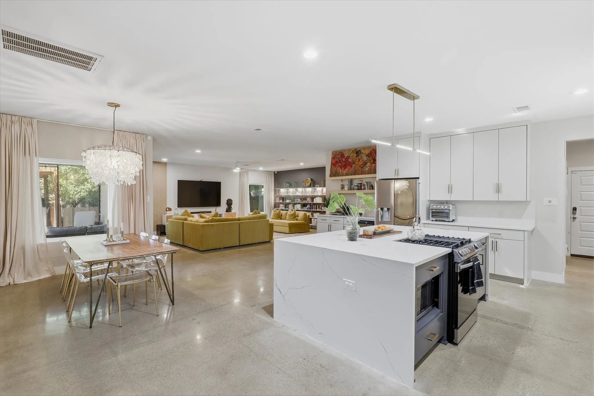 Open-concept living space with polished concrete flooring, recessed lighting, and a modern kitchen island with an integrated cooktop and microwave