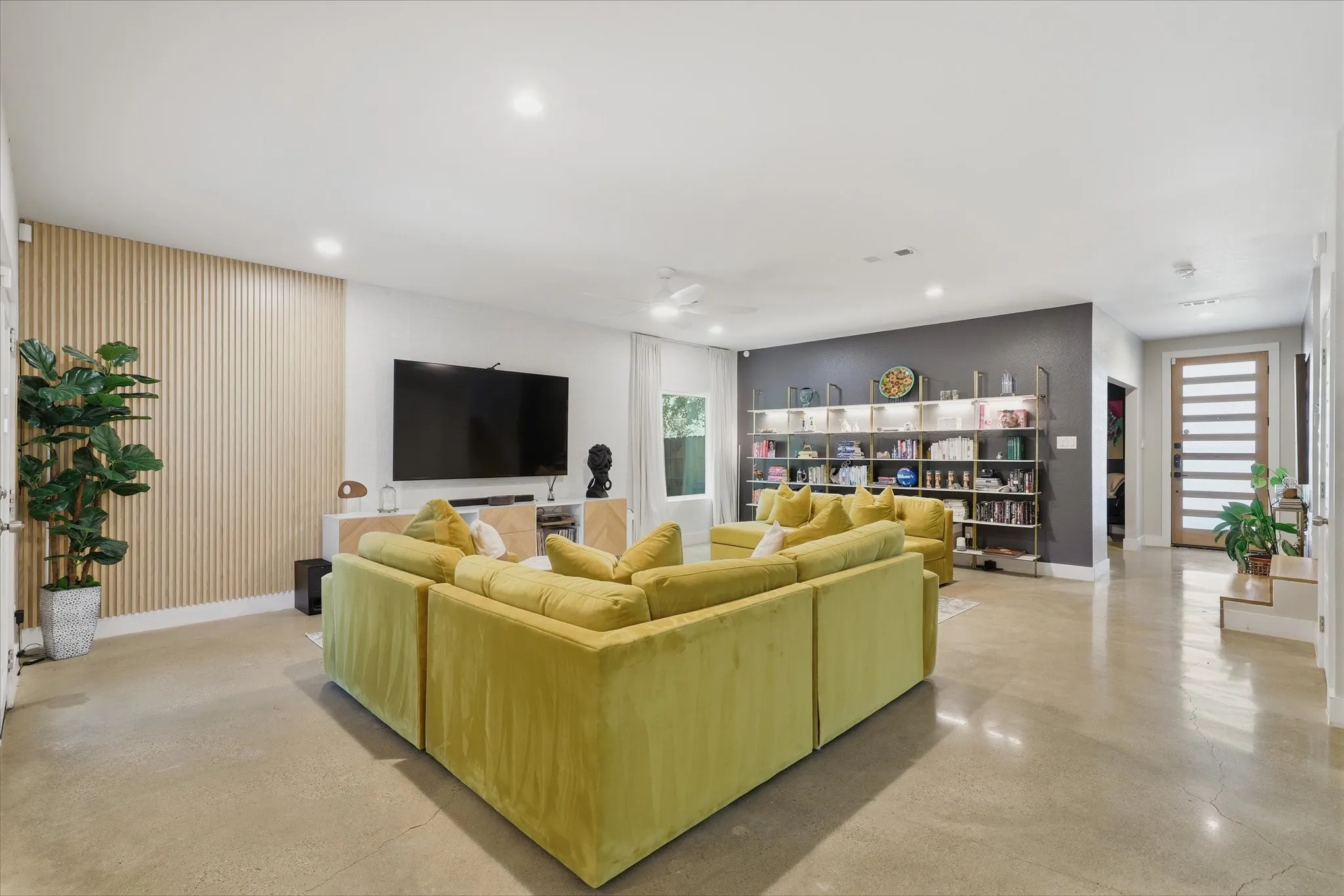 Recessed lighting, light-toned flooring, built-in shelving, a wood-slat accent wall, and a slatted entry door