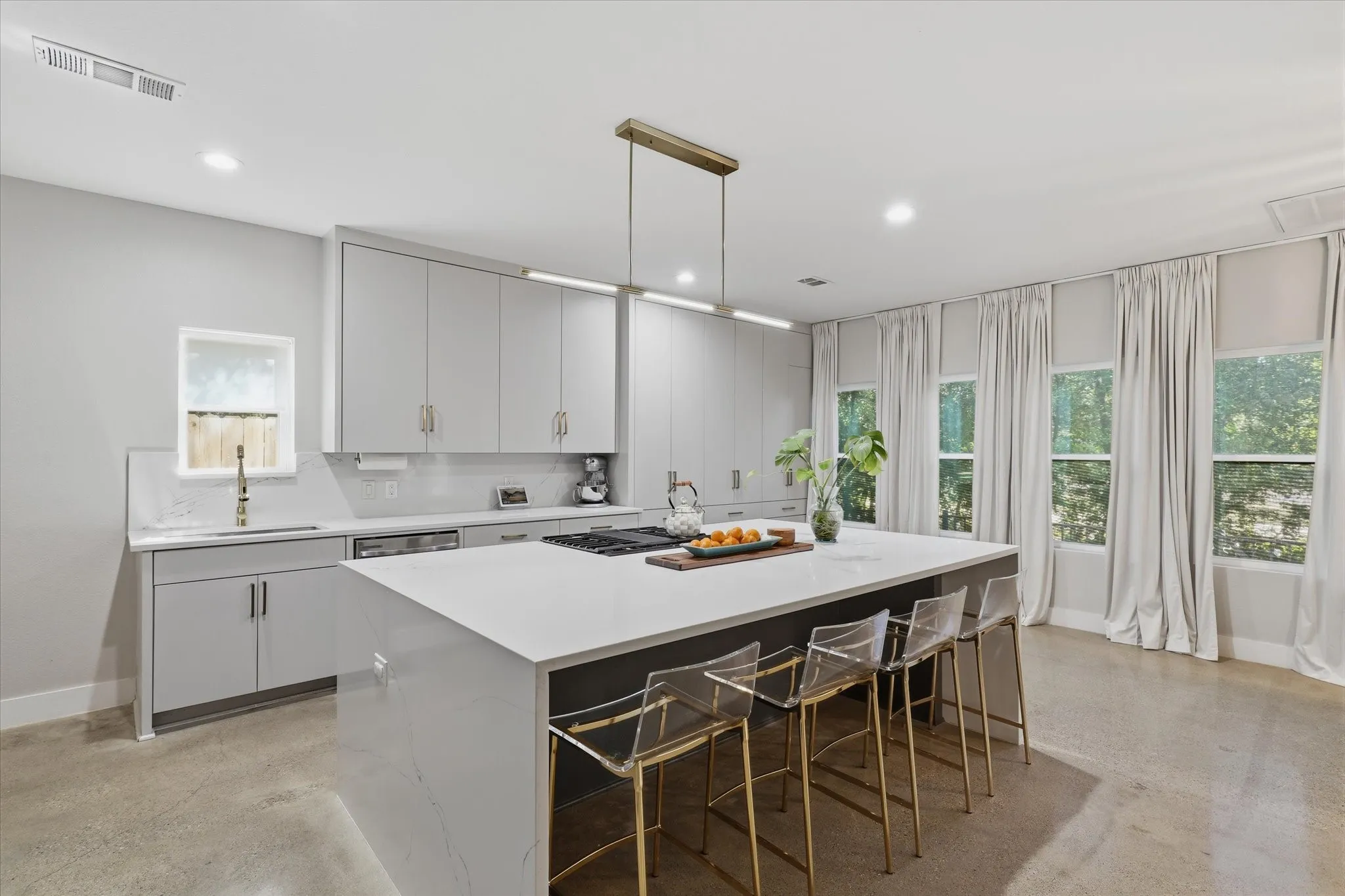 Sleek kitchen featuring an oversized island with countertop seating, integrated gas cooktop, recessed lighting, and ample cabinetry