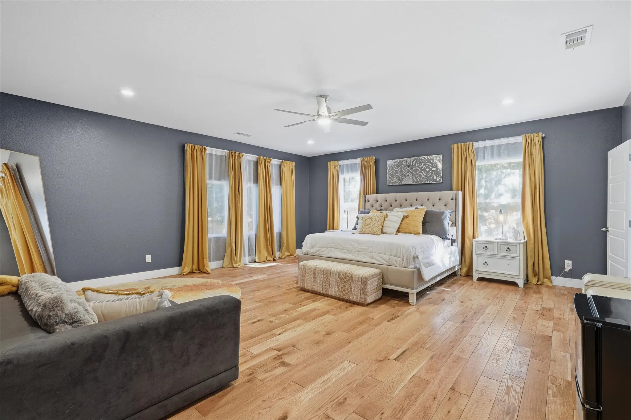 Recessed lighting, wood-finish flooring, ceiling fan, multiple windows with natural light, and a white paneled door