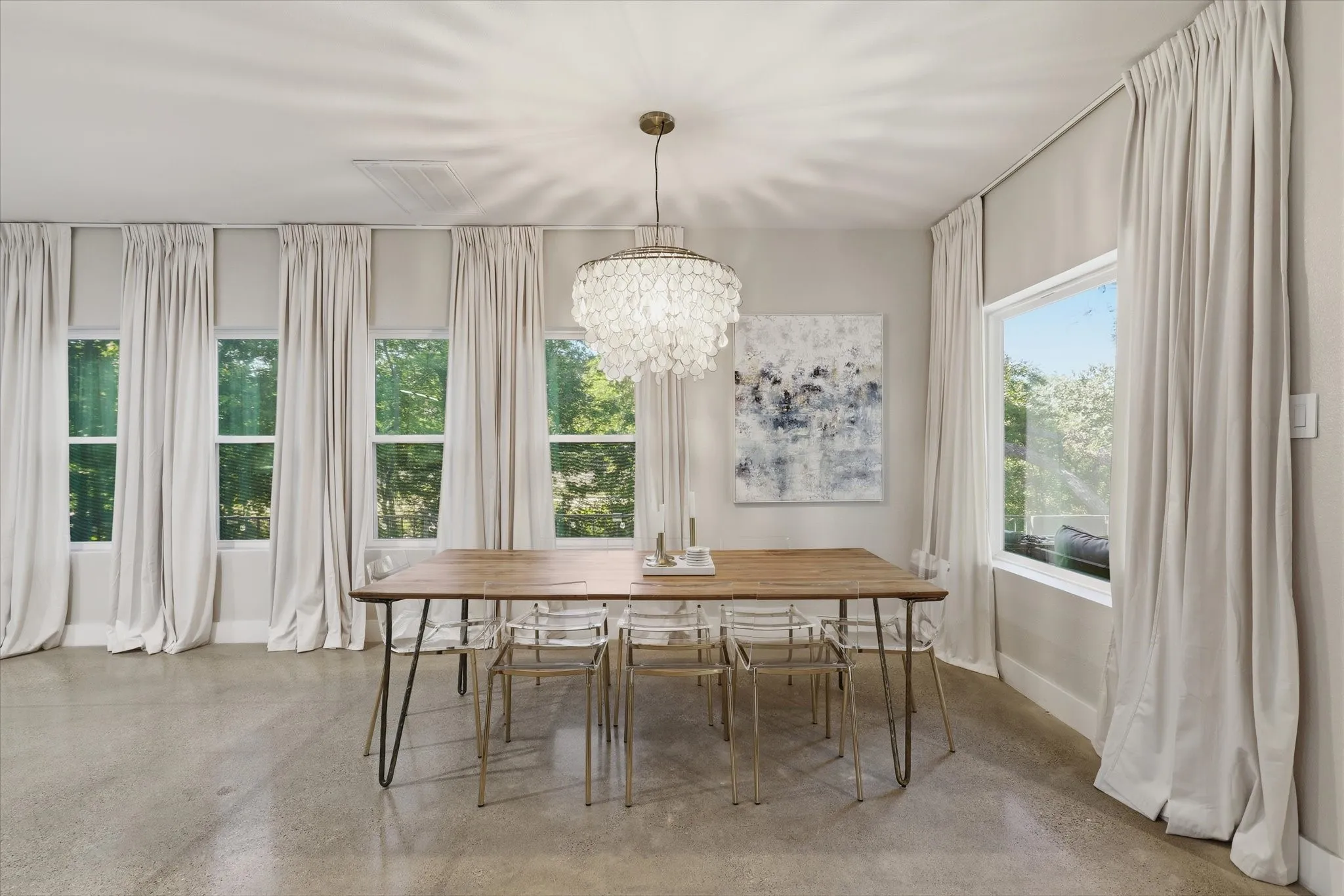 Polished concrete flooring, multiple tall windows, modern chandelier, and light-toned wall paint
