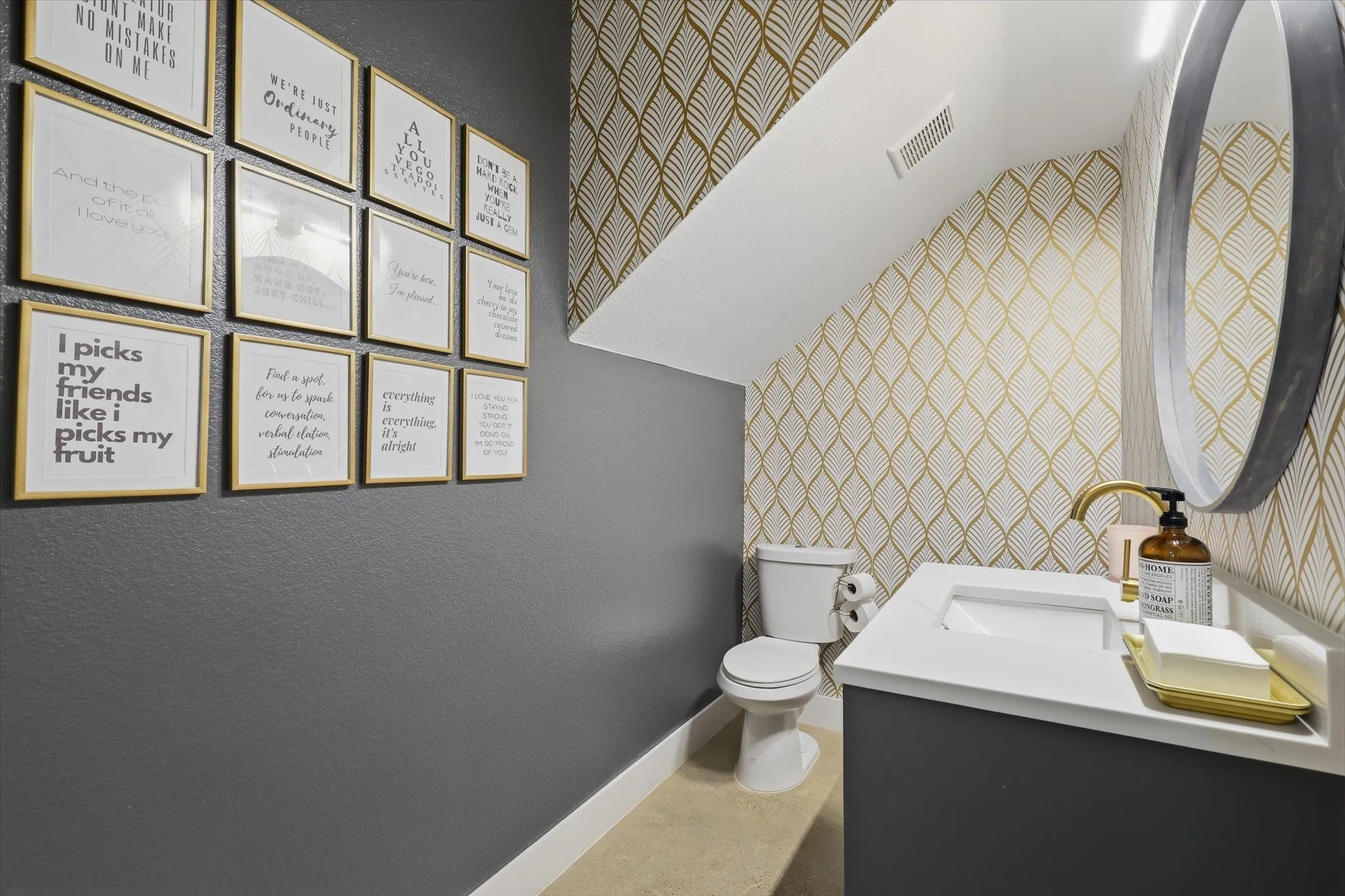 Powder room featuring a single vanity with an integrated sink, a gold-finish faucet, and a round wall-mounted mirror