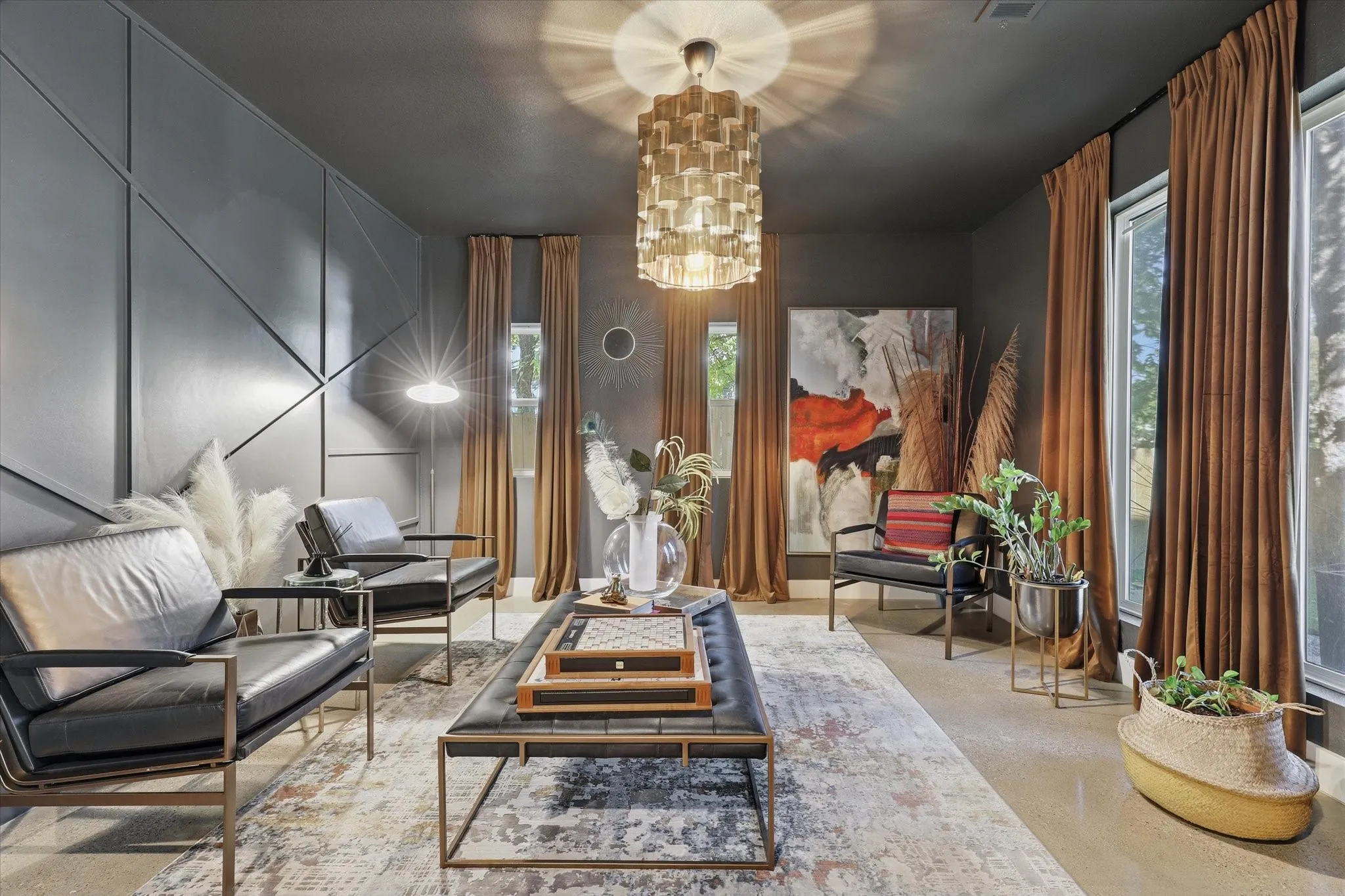 Recessed ceiling with an ornate chandelier, panel wall accents, tall windows with full-length drapery, and concrete flooring