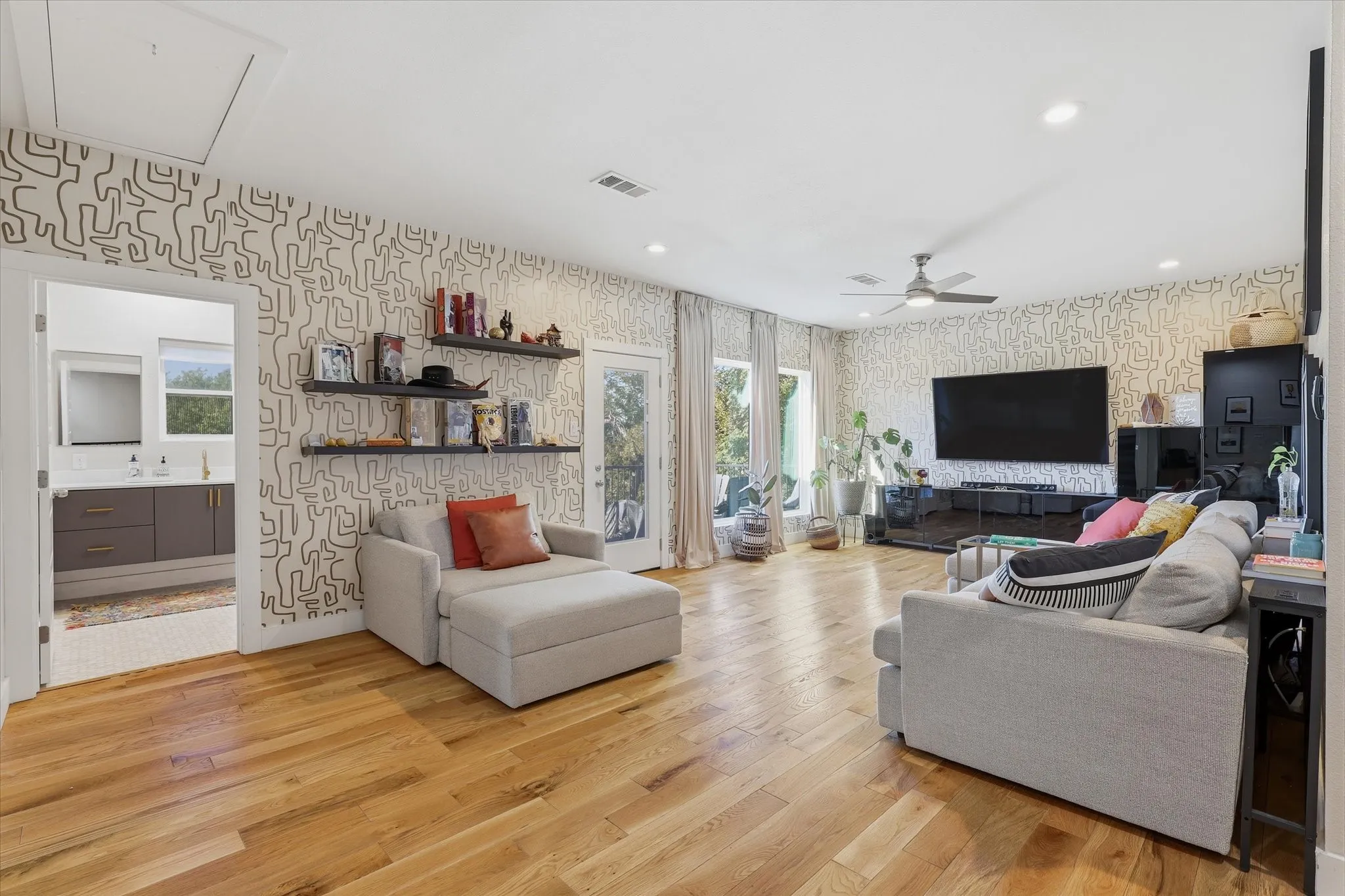 Open concept room featuring wood-finish flooring, patterned accent walls, recessed lighting, and a ceiling fan