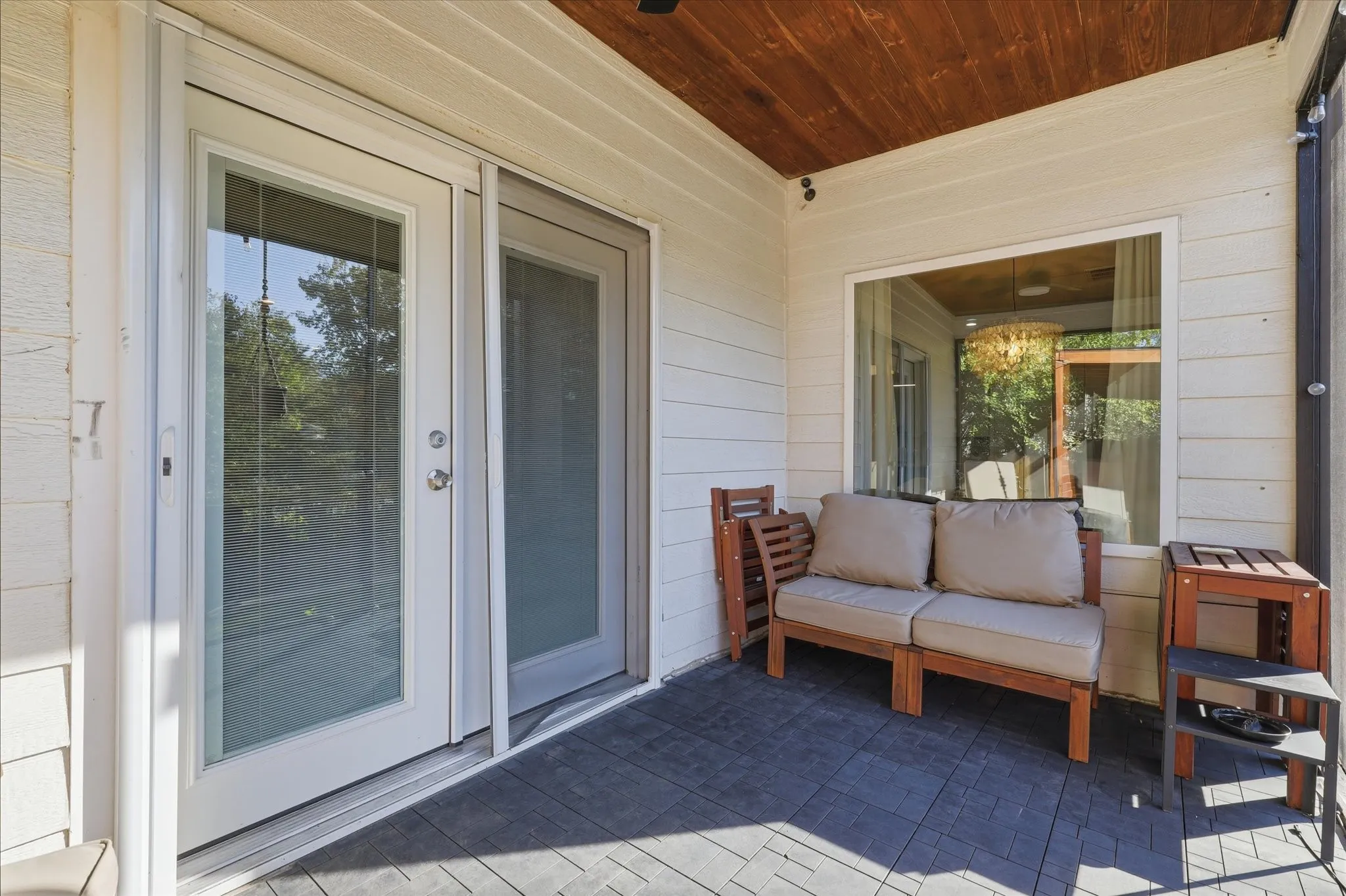 Covered outdoor patio with a wood-finish ceiling, white horizontal siding, and a large window