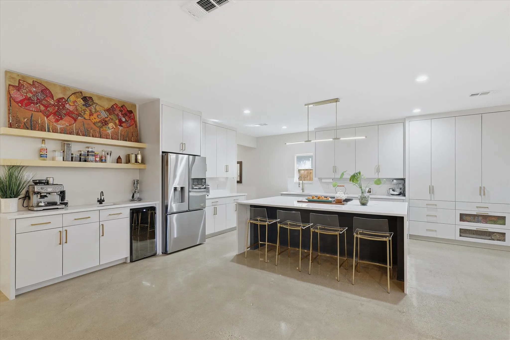 Spacious kitchen featuring white cabinetry, a large kitchen island with seating, a built-in beverage refrigerator, and stainless steel appliances