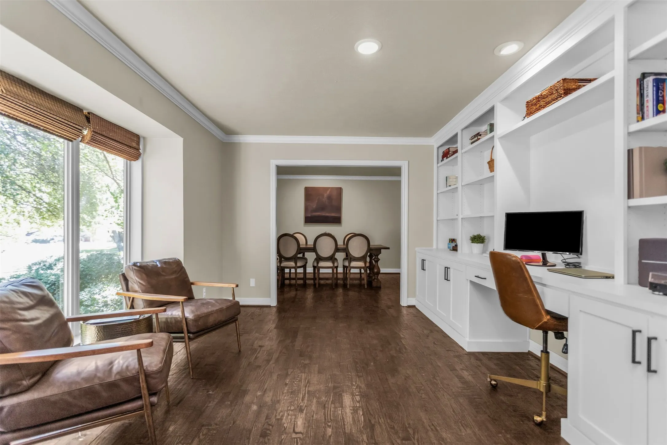 Sophisticated open-concept living space featuring dark wood-finish flooring, recessed ceiling lighting, and extensive built-in white cabinetry with shelving throughout