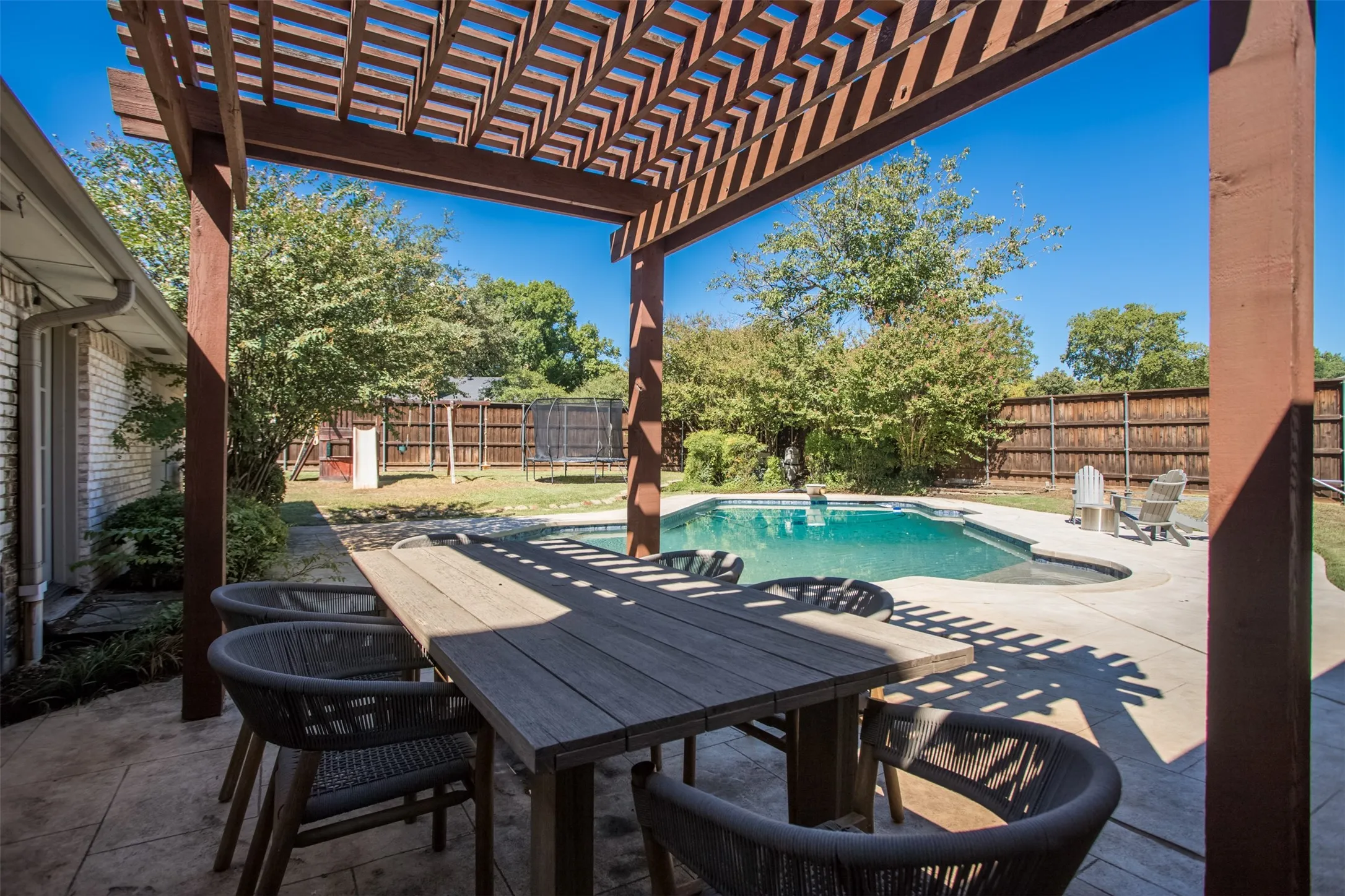 Covered patio with a wooden pergola, concrete surround, and an in-ground swimming pool