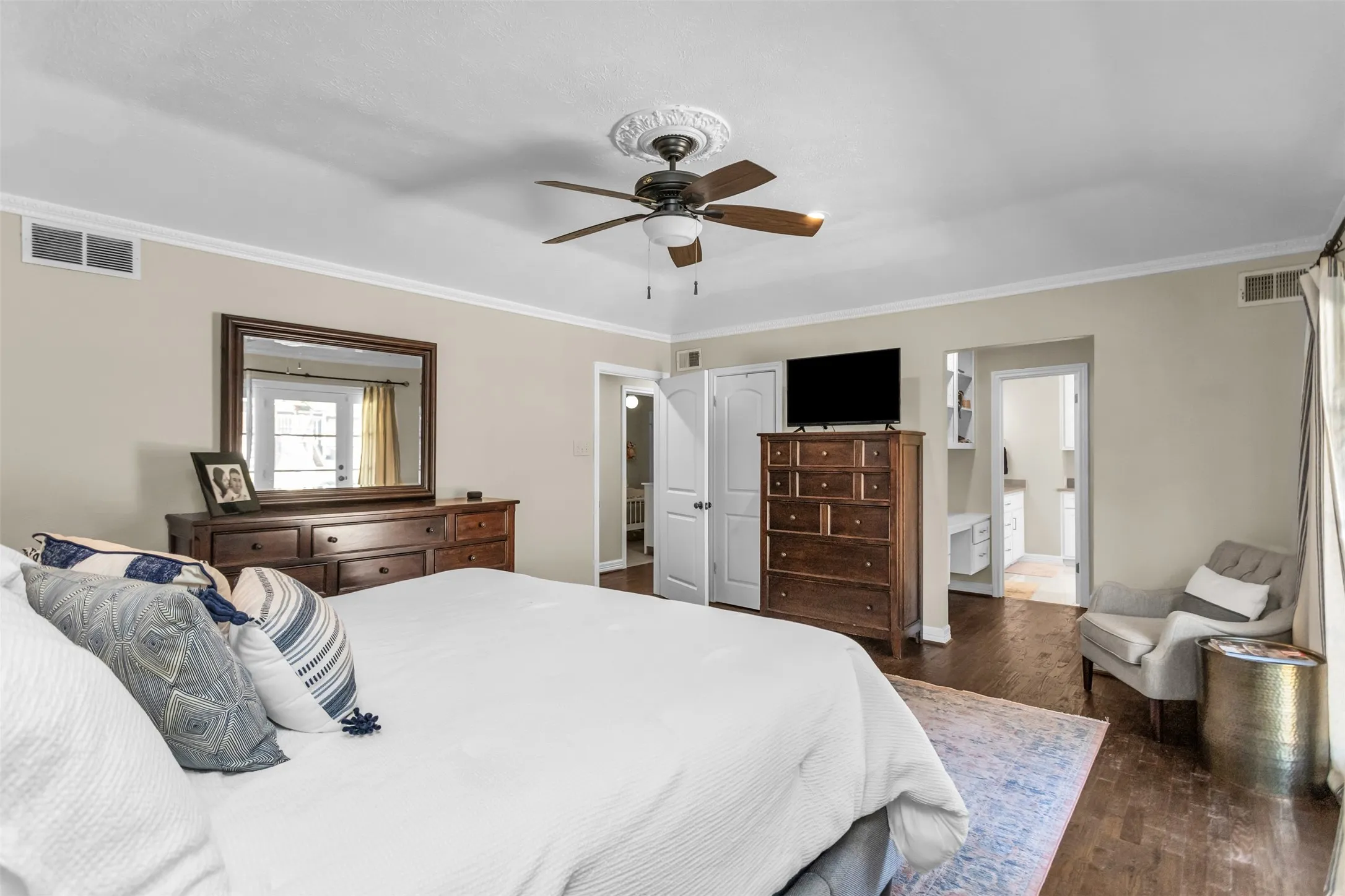 Spacious primary bedroom featuring hardwood flooring, a ceiling fan with integrated lighting, and an ensuite bathroom