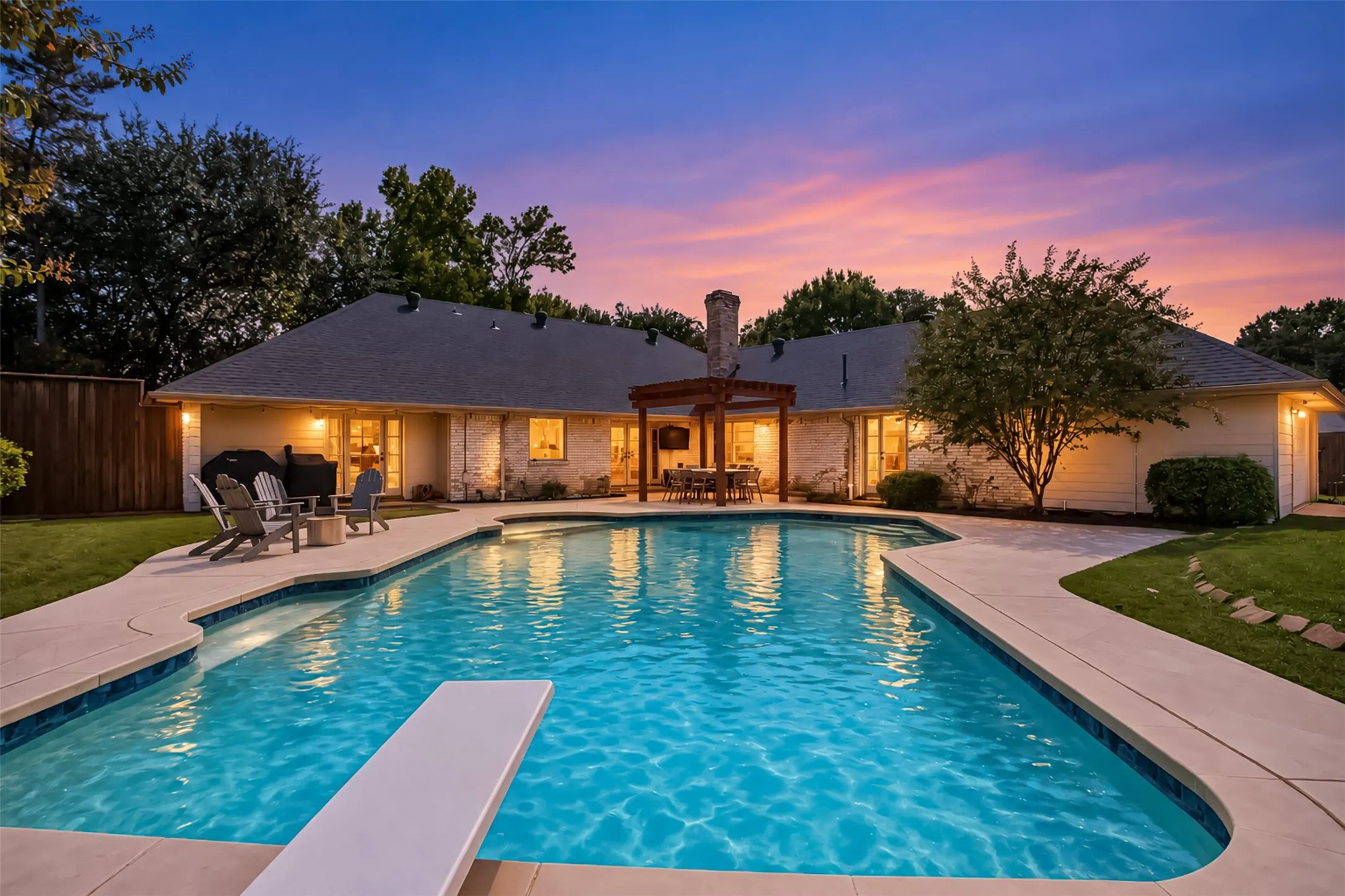 White brick exterior with multiple windows, a prominent in-ground swimming pool, and a diving board