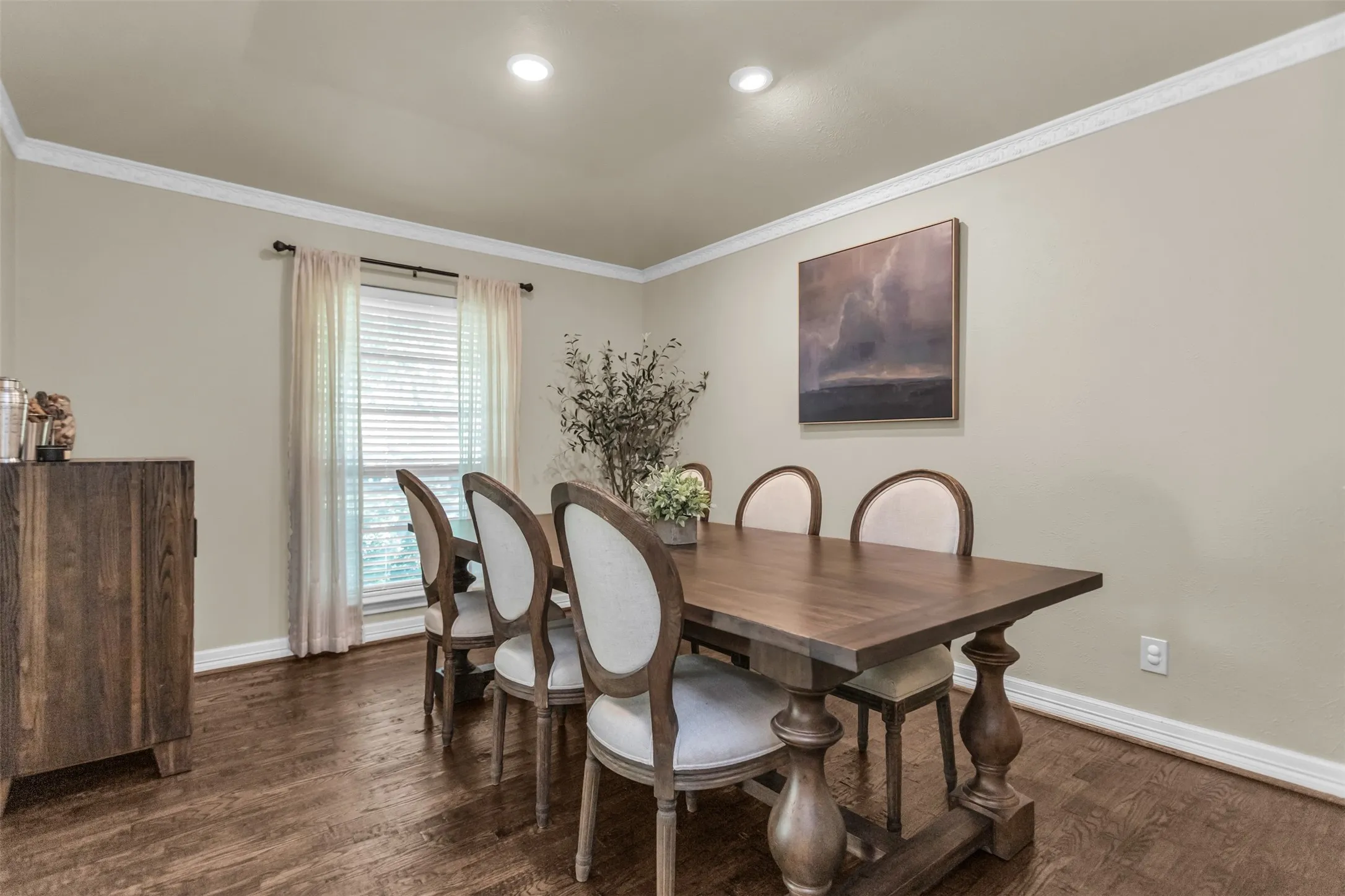 Recessed lighting illuminates the room, featuring crown molding, neutral wall tones, and wood-finish flooring