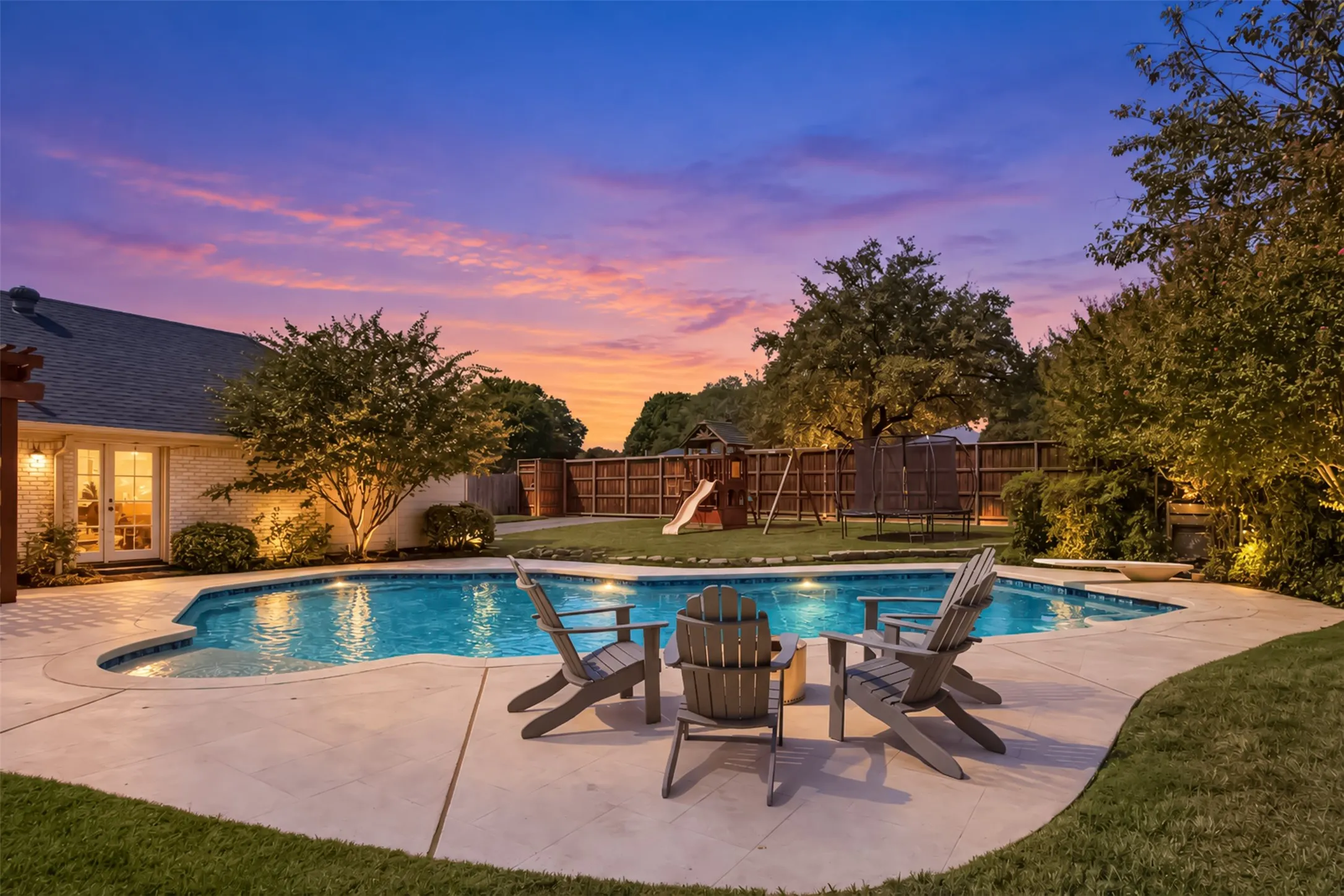 Expansive backyard with a free-form swimming pool, concrete pool deck, and mature landscaping