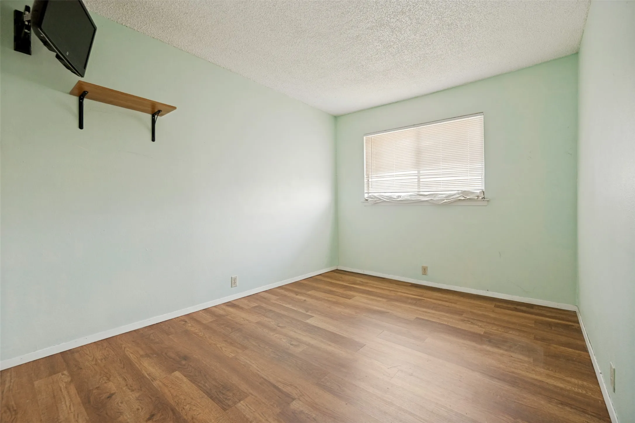 Wood-finish flooring, light-toned walls, and a built-in wall shelf