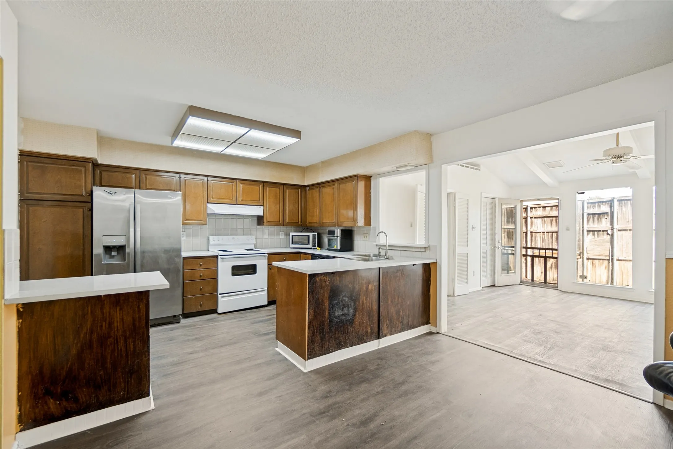 Kitchen featuring wood-finish cabinetry, stainless steel refrigerator, white electric range, and wood-finish flooring