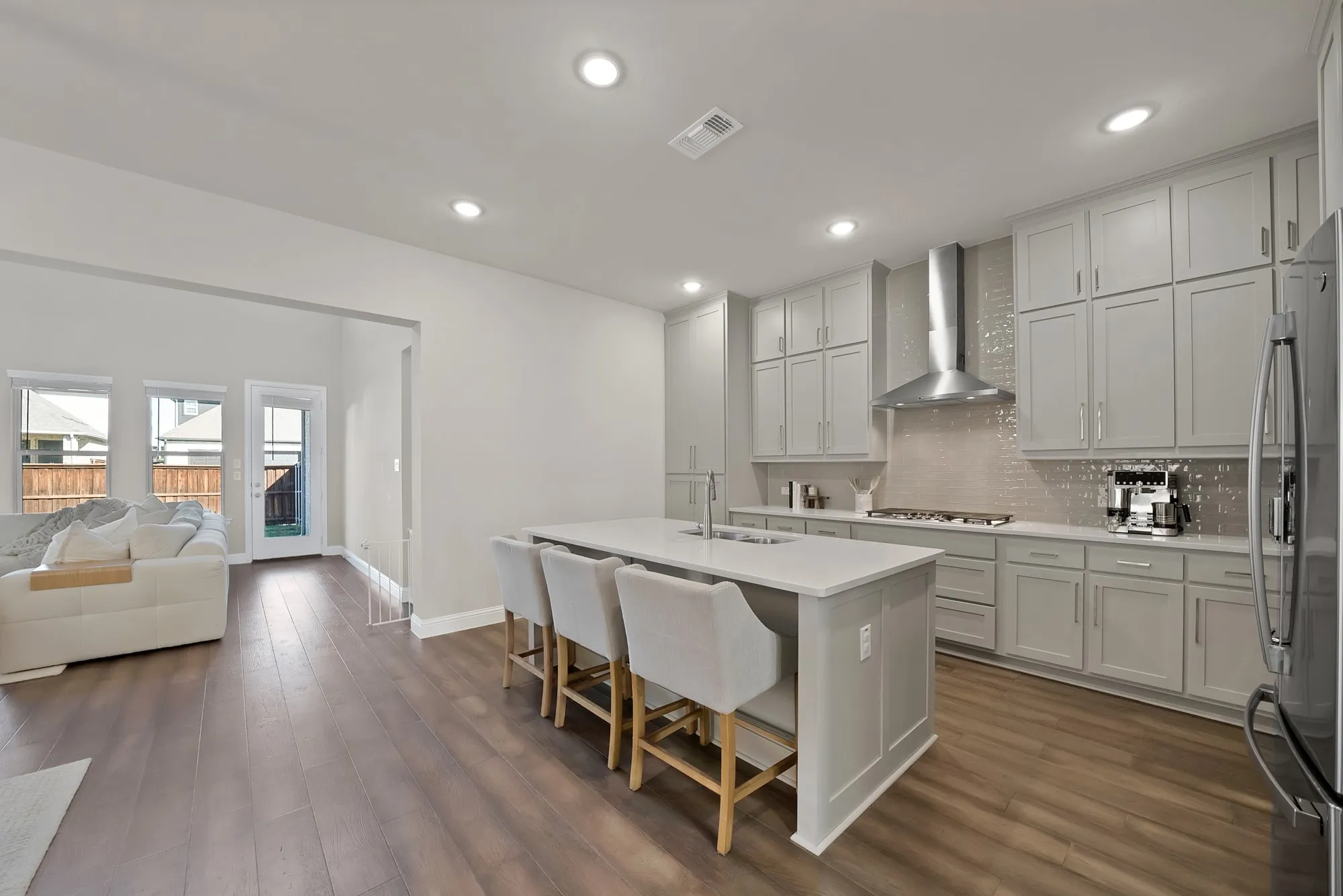 Recessed lighting throughout, wood-finish flooring, kitchen island with seating, stainless steel appliances, and extensive cabinetry