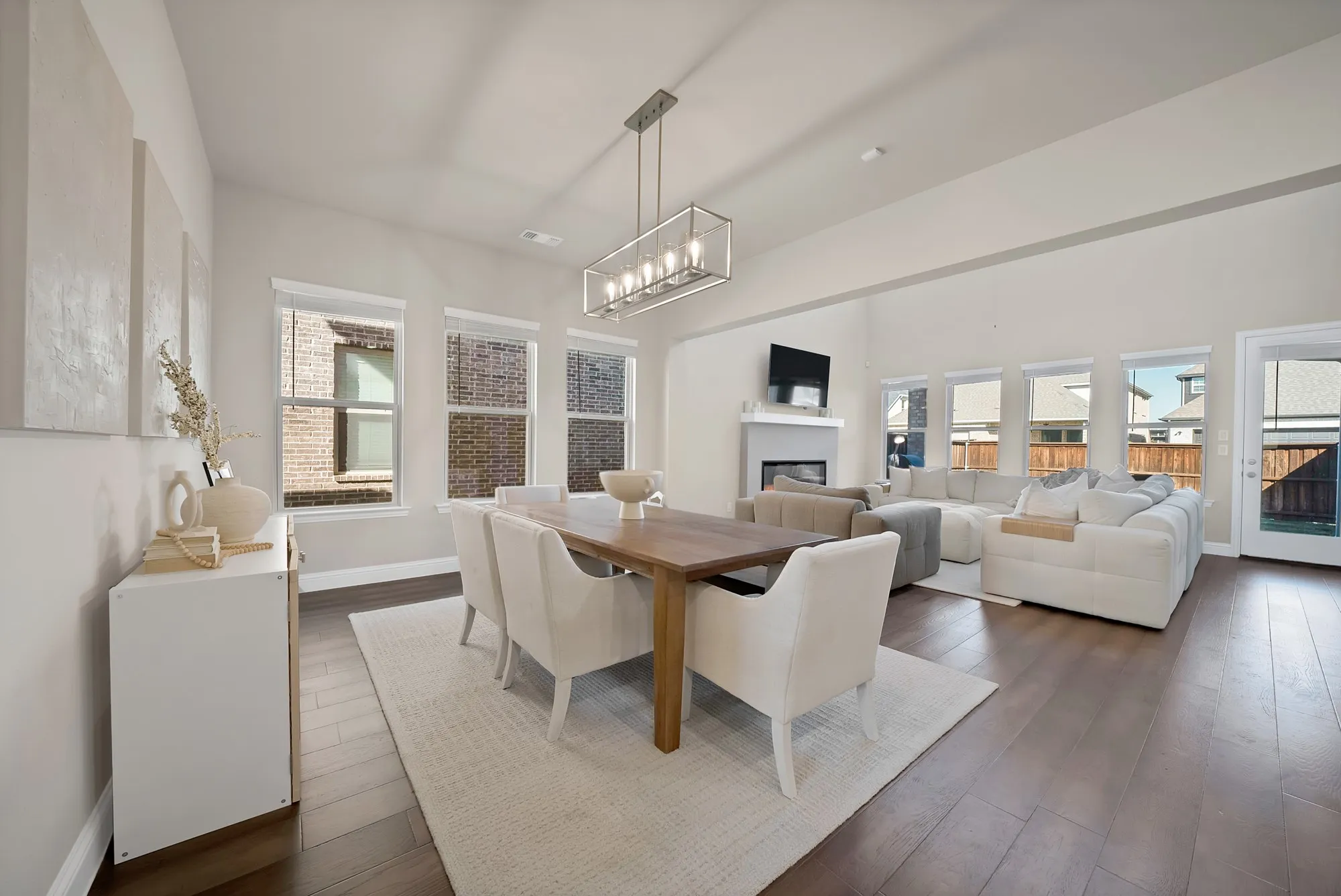 Open-concept living area featuring high ceilings, wood-finish flooring, and multiple windows