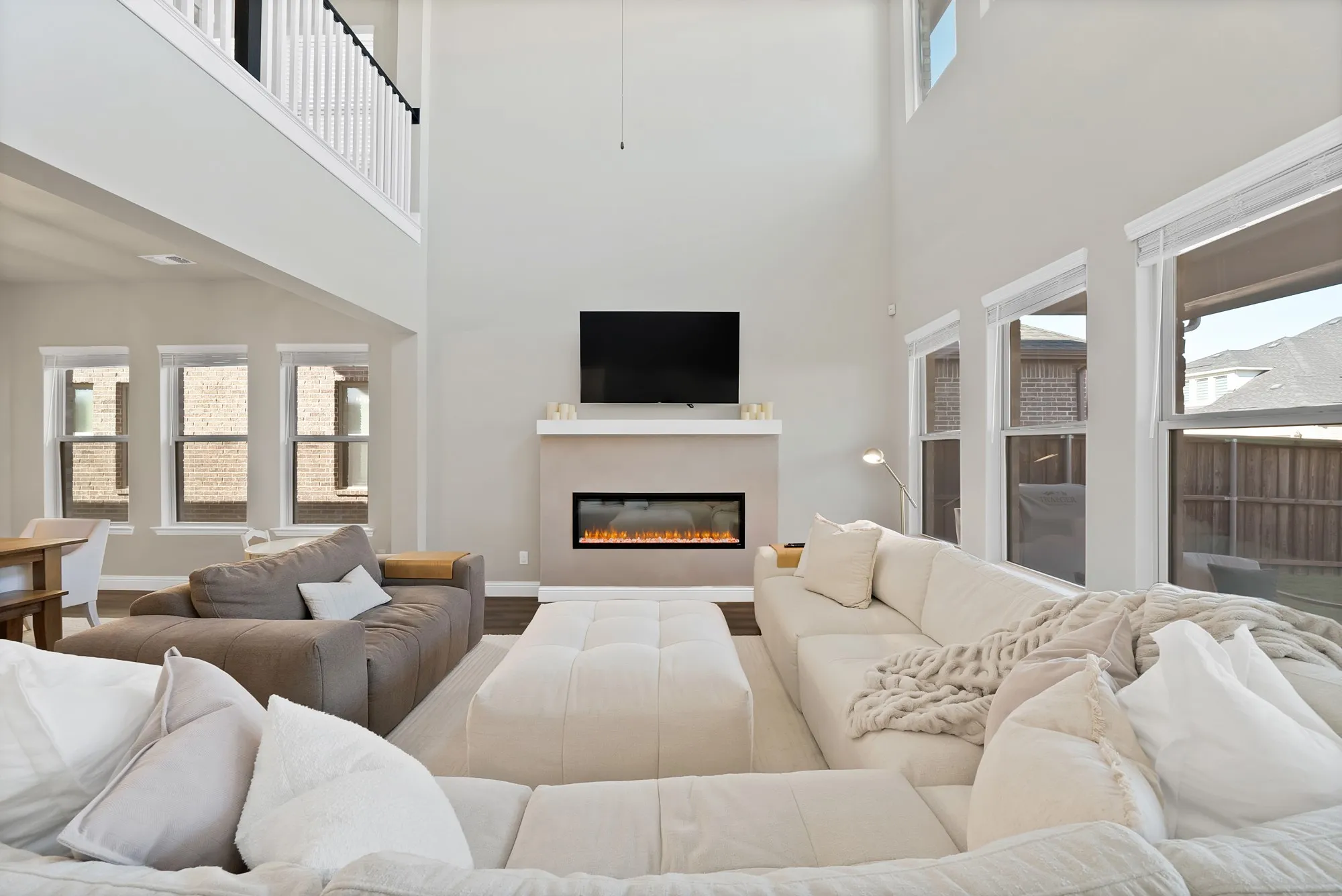 Two-story living area with high ceilings, multiple windows, built-in fireplace, and upper-level railing