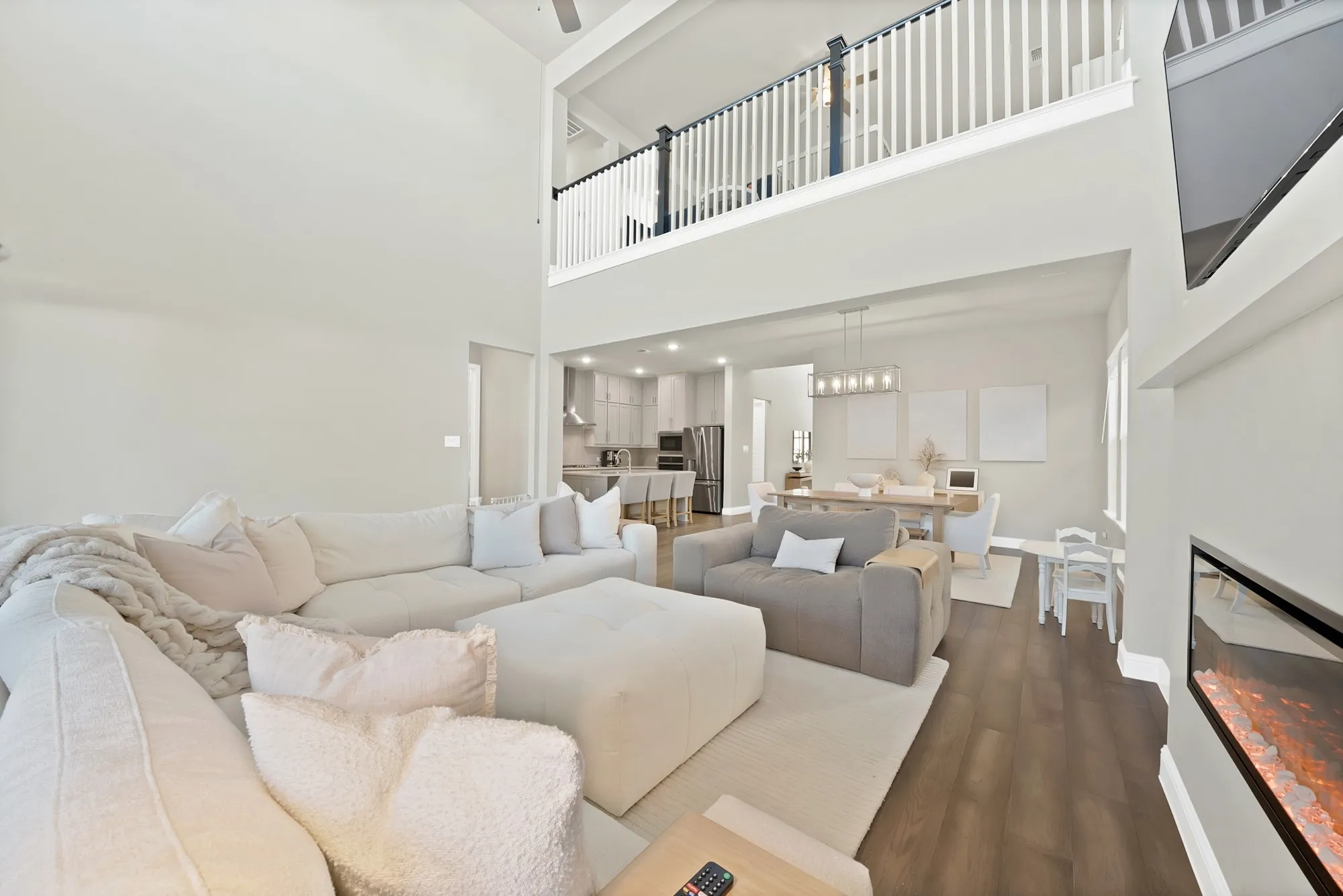 Two-story living area with high ceilings, wood-finish flooring, and an upper-level railing overlooking the space