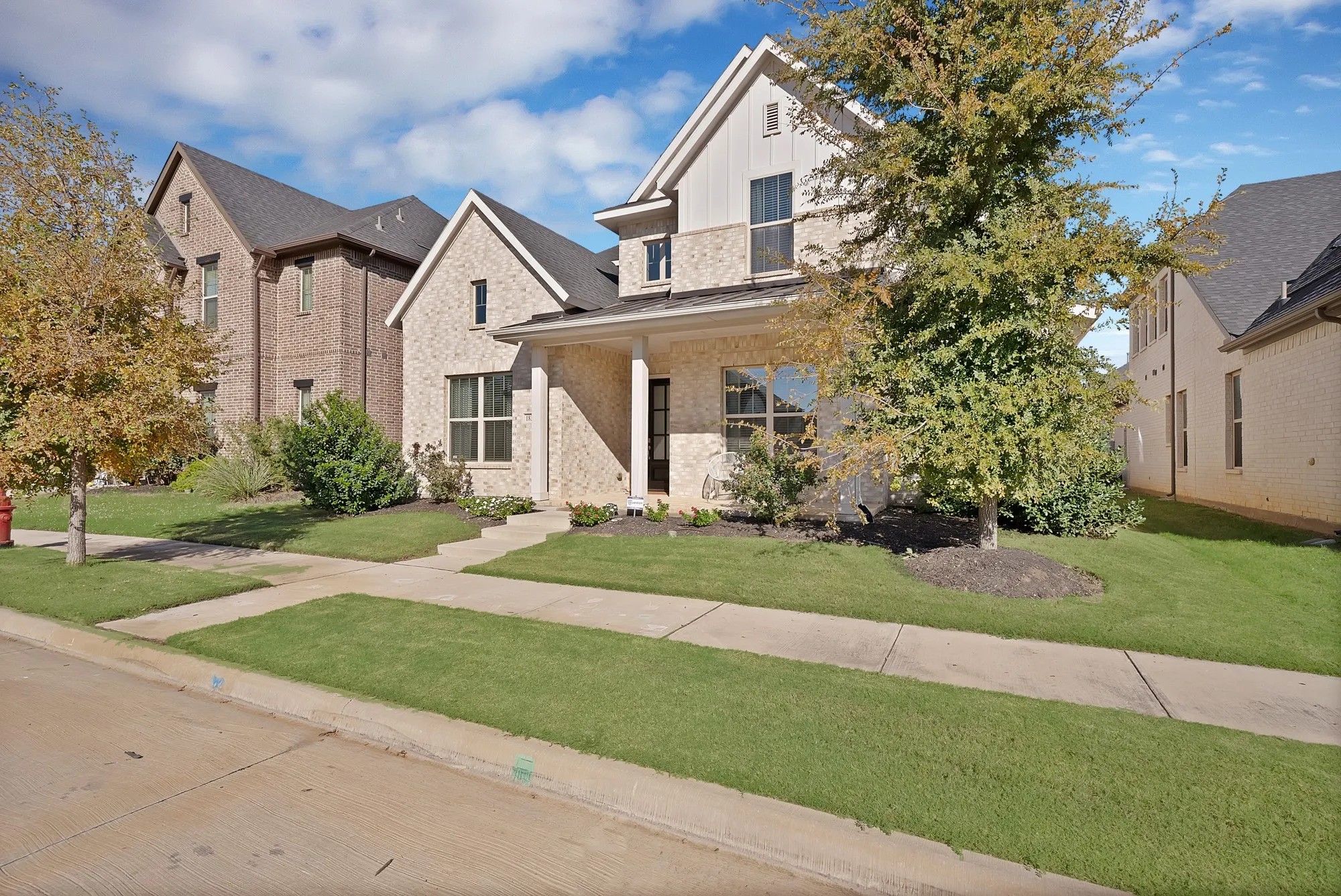 Two-story residence featuring light-colored brick and siding accents