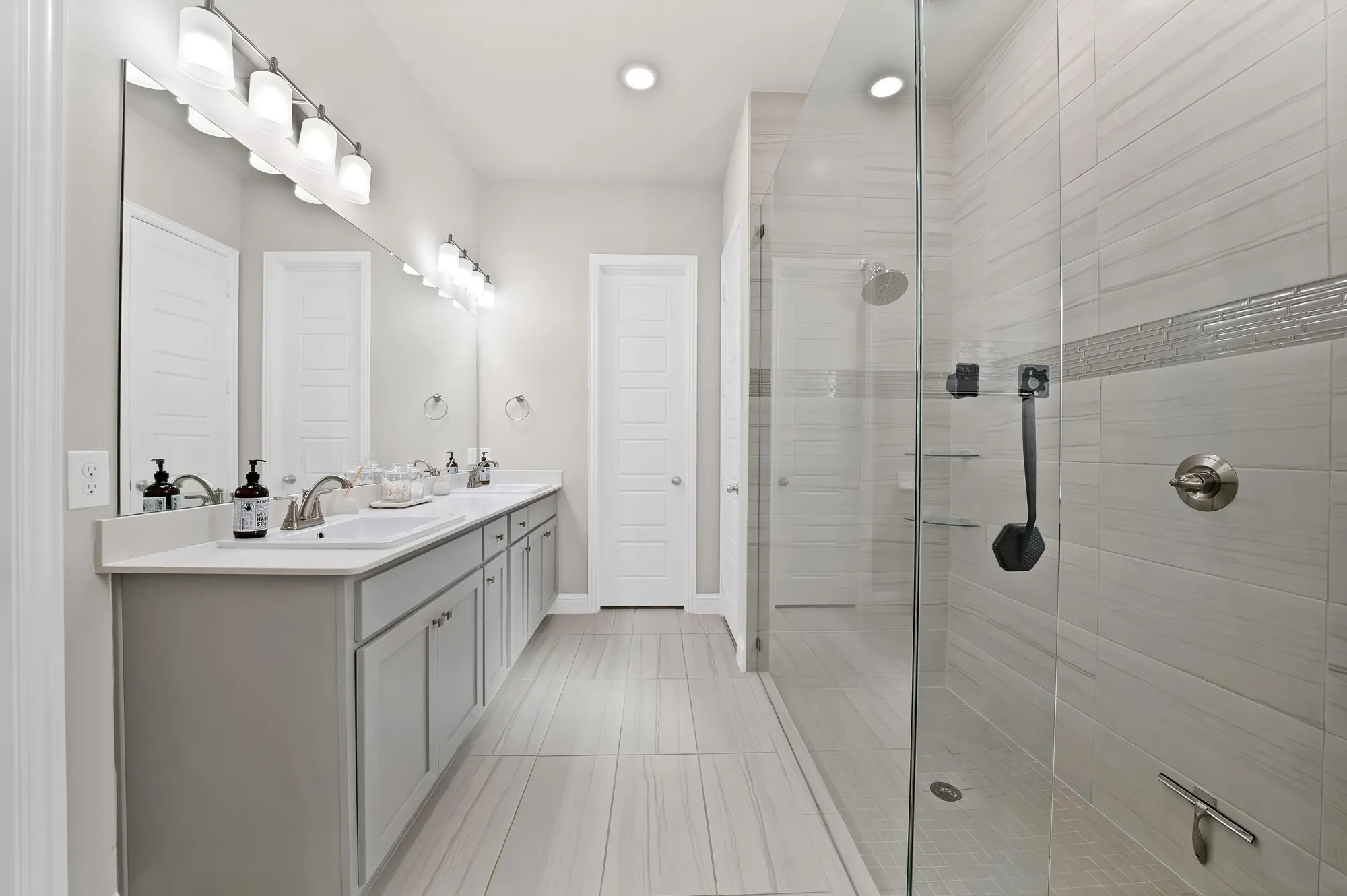 Dual vanity with undermount sinks, light gray cabinetry, and a full-width mirror