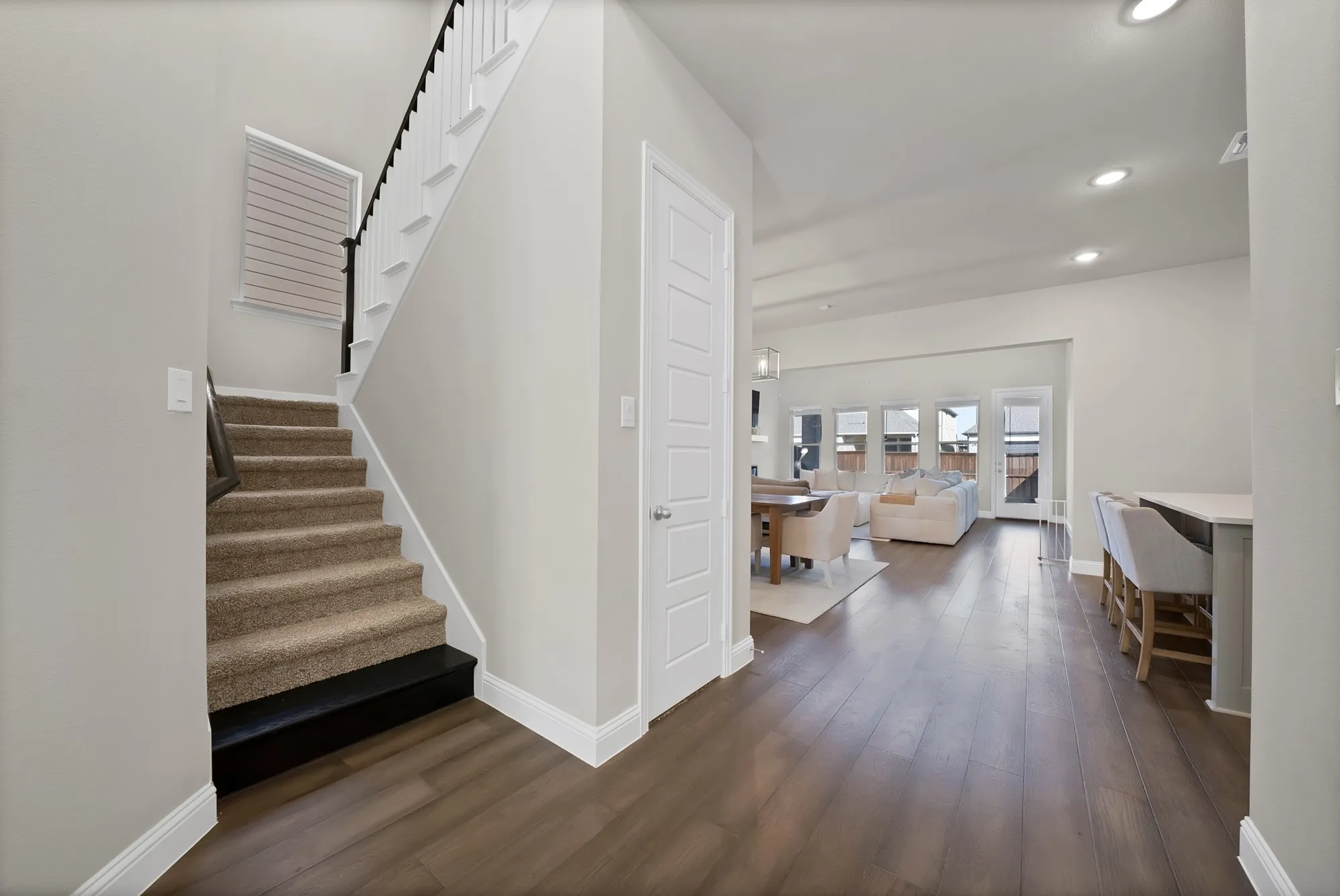Open-concept living area featuring wood-finish flooring, recessed lighting, and multiple windows