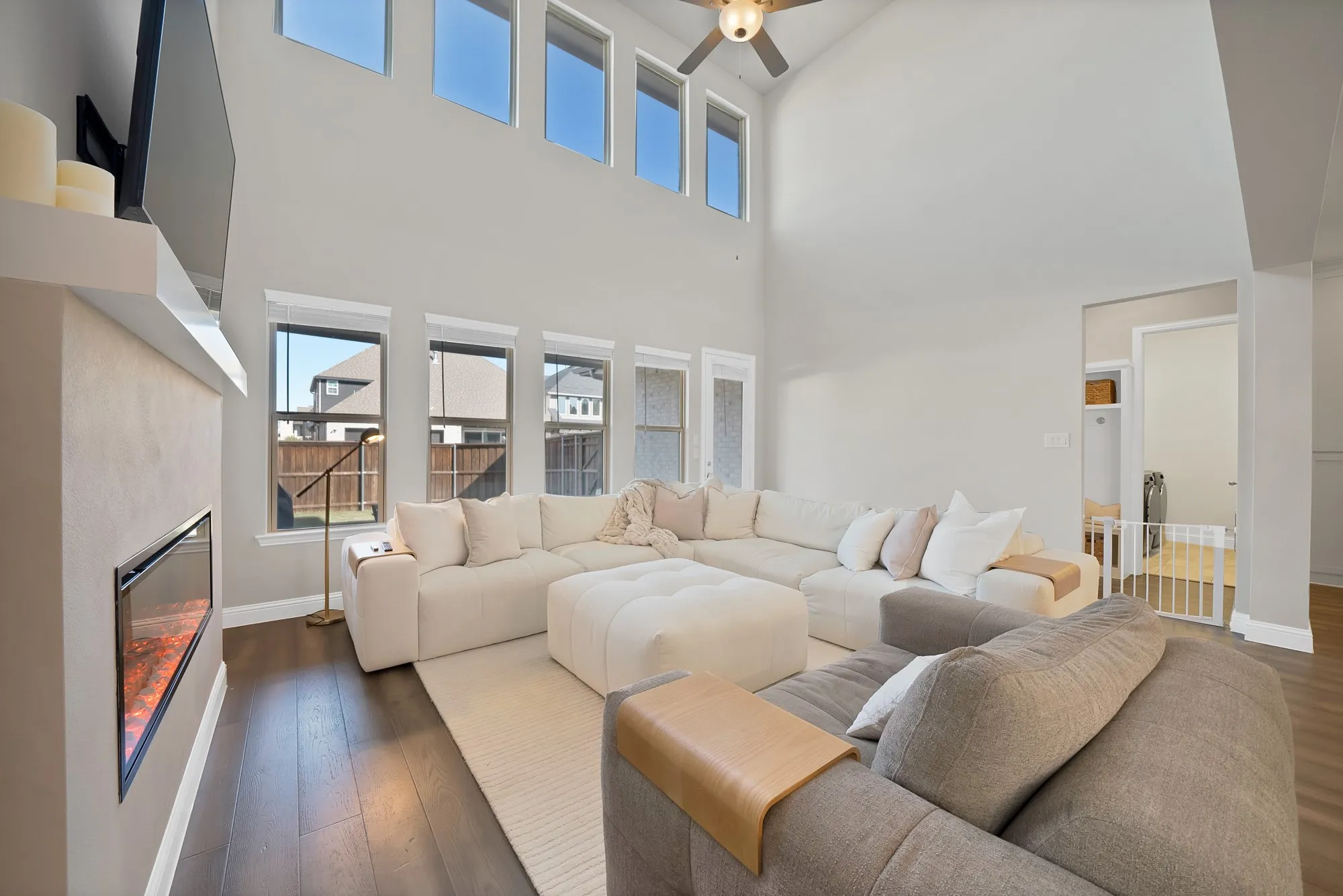 Two-story living area with high ceilings, dark wood-finish flooring, and an electric fireplace