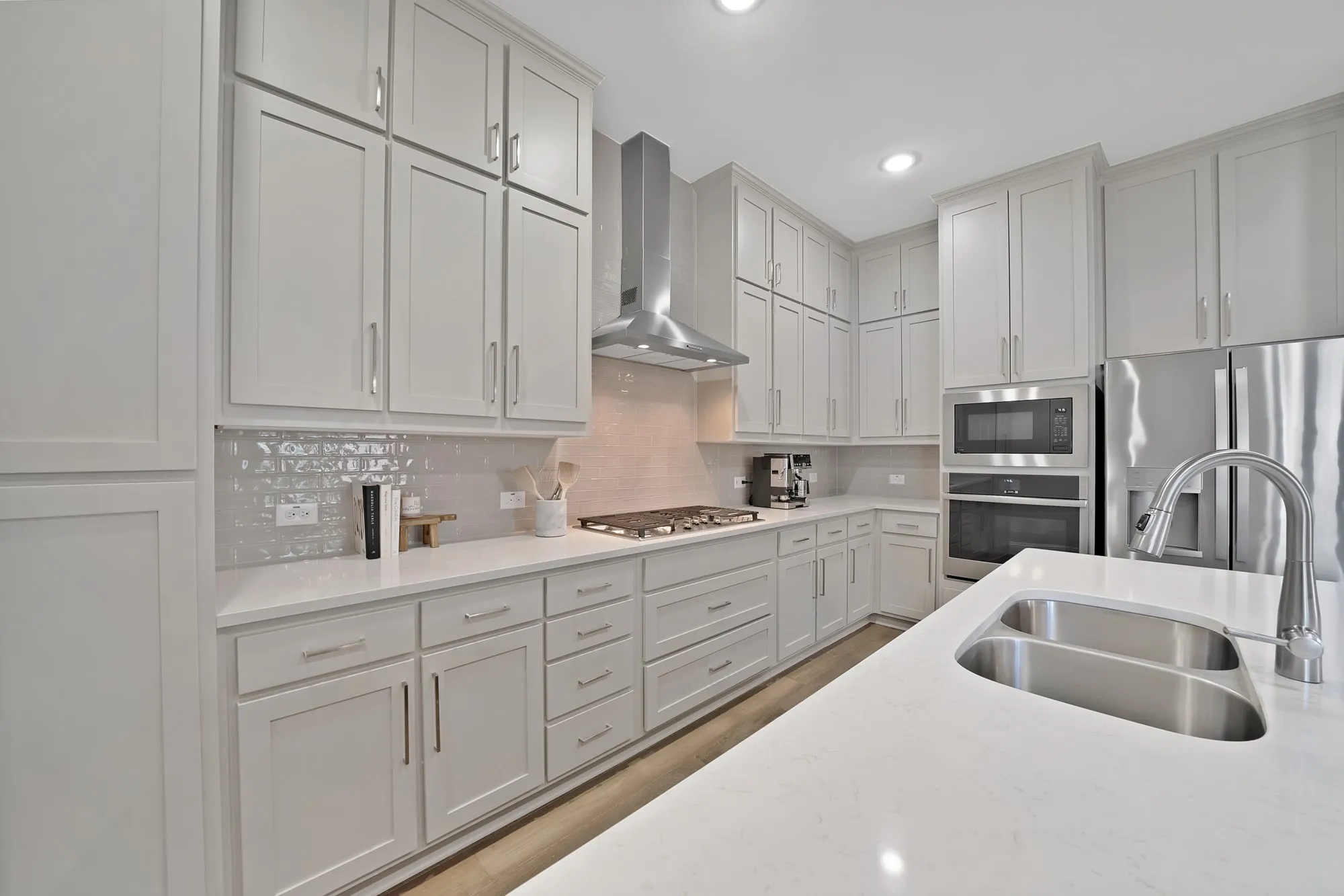 Expansive kitchen featuring abundant cabinetry, stainless steel appliances, a double basin sink, and light-toned countertops