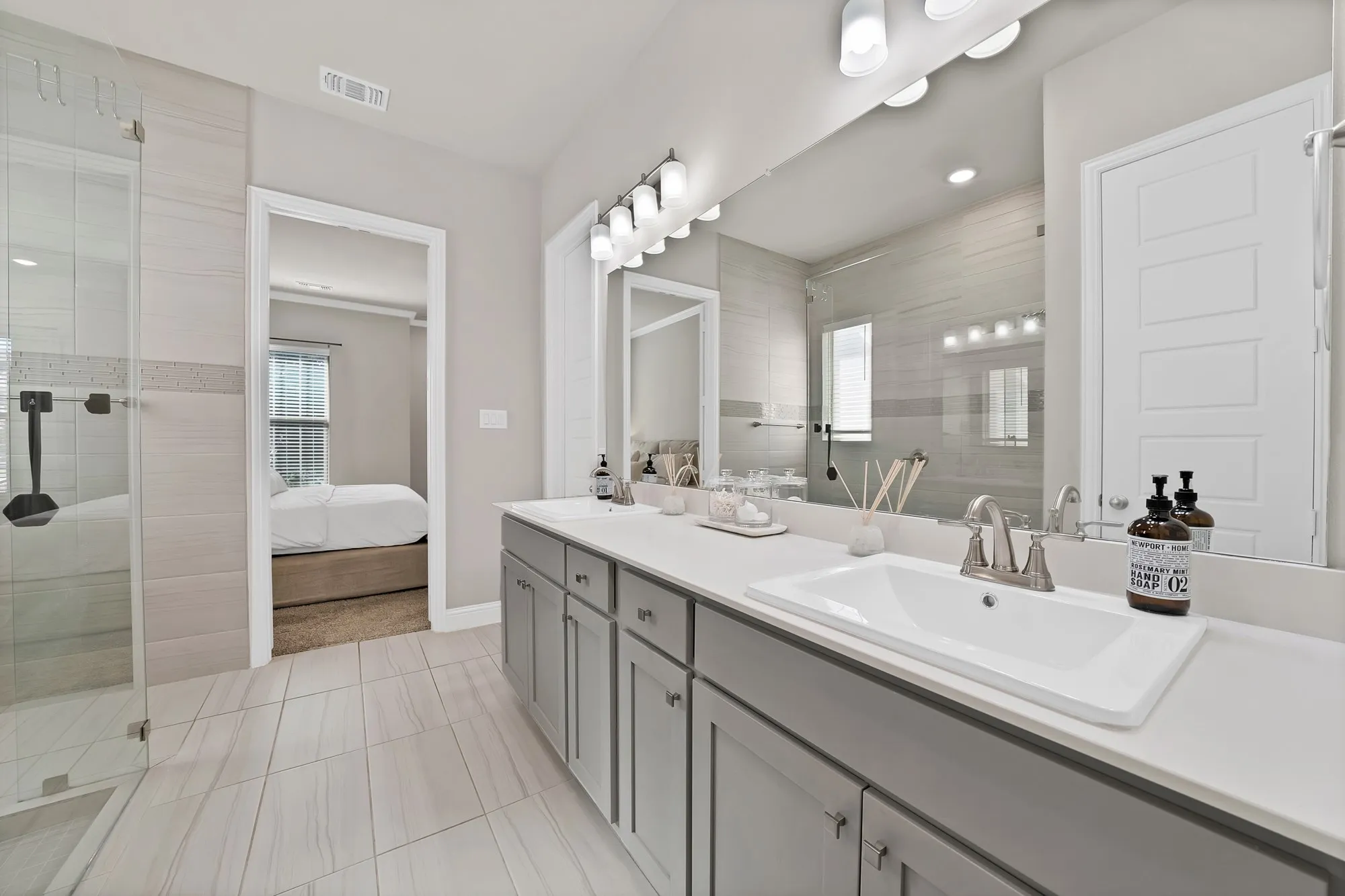 Dual sink vanity with light gray cabinetry, white countertops, and brushed nickel fixtures