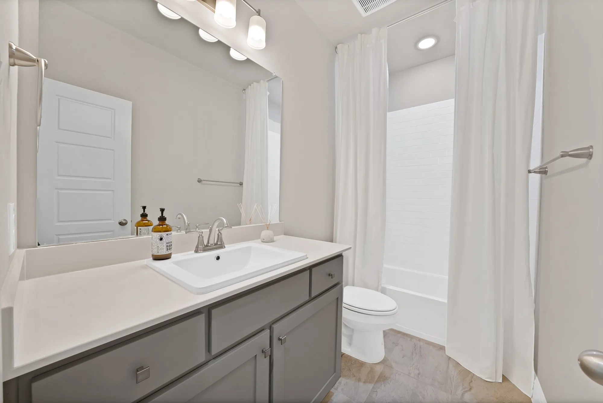 Vanity with an integrated rectangular sink, gray cabinetry, and a light-toned countertop