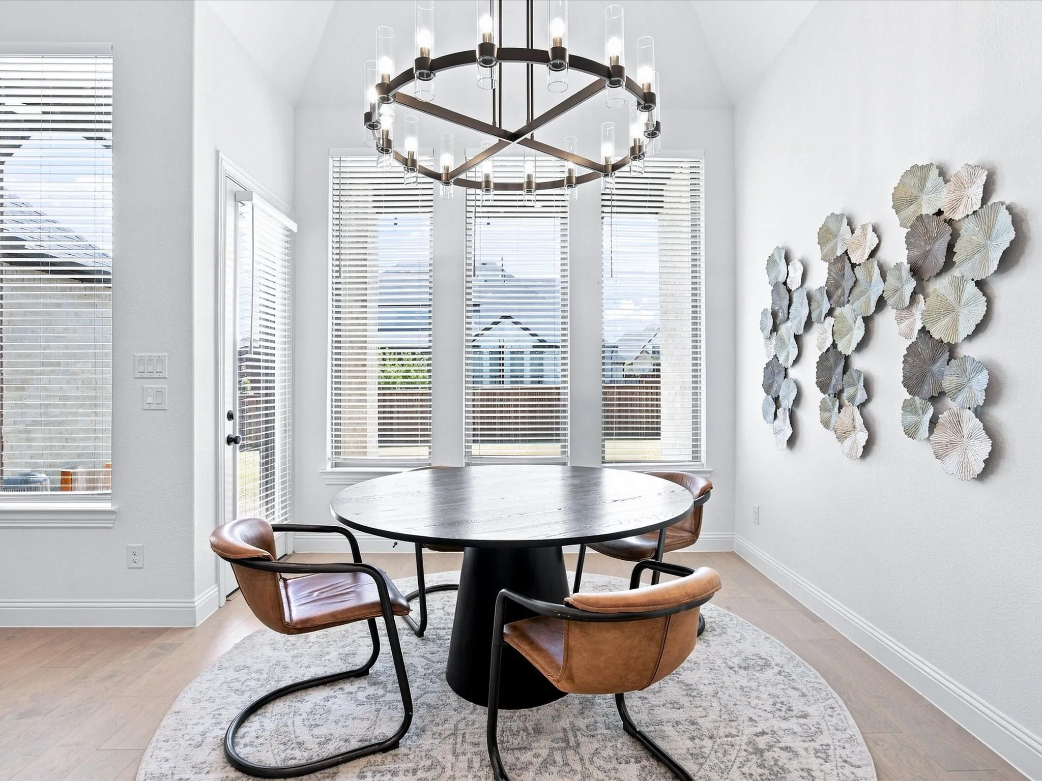 Vaulted ceiling with an overhead chandelier, large windows with horizontal blinds, and wood-finish flooring