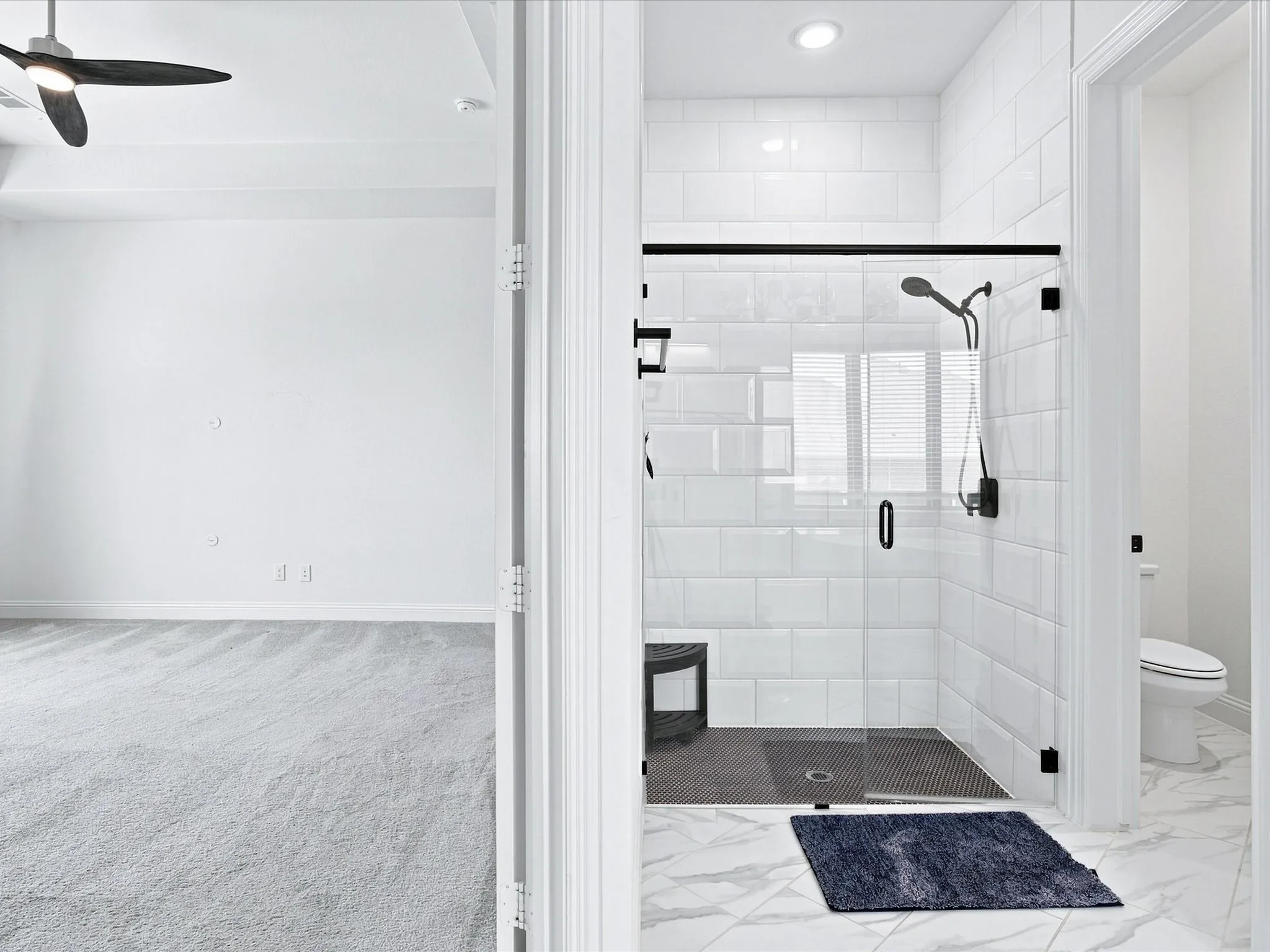 Recessed lighting, ceiling fan, white subway tile shower, clear glass shower enclosure, and marble-look floor tile