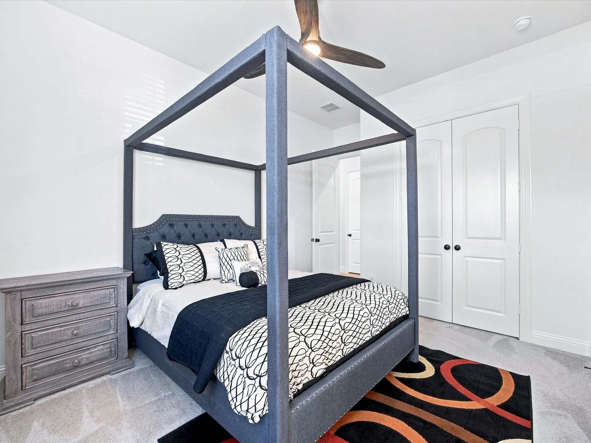 Carpeted room featuring a ceiling fan, white paneled doors, and white walls