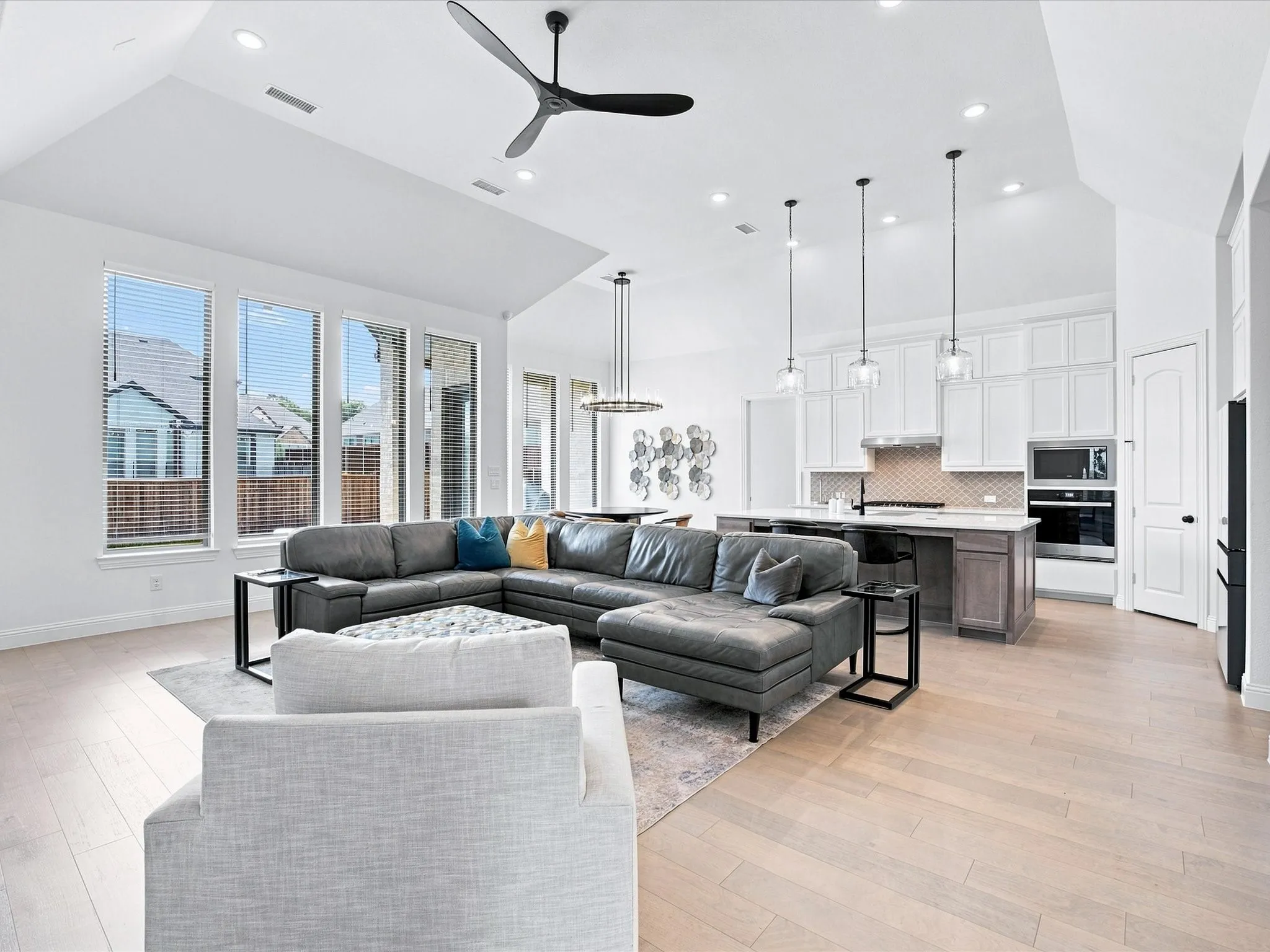 Vaulted ceilings, recessed lighting, and large windows illuminate this open-concept living space