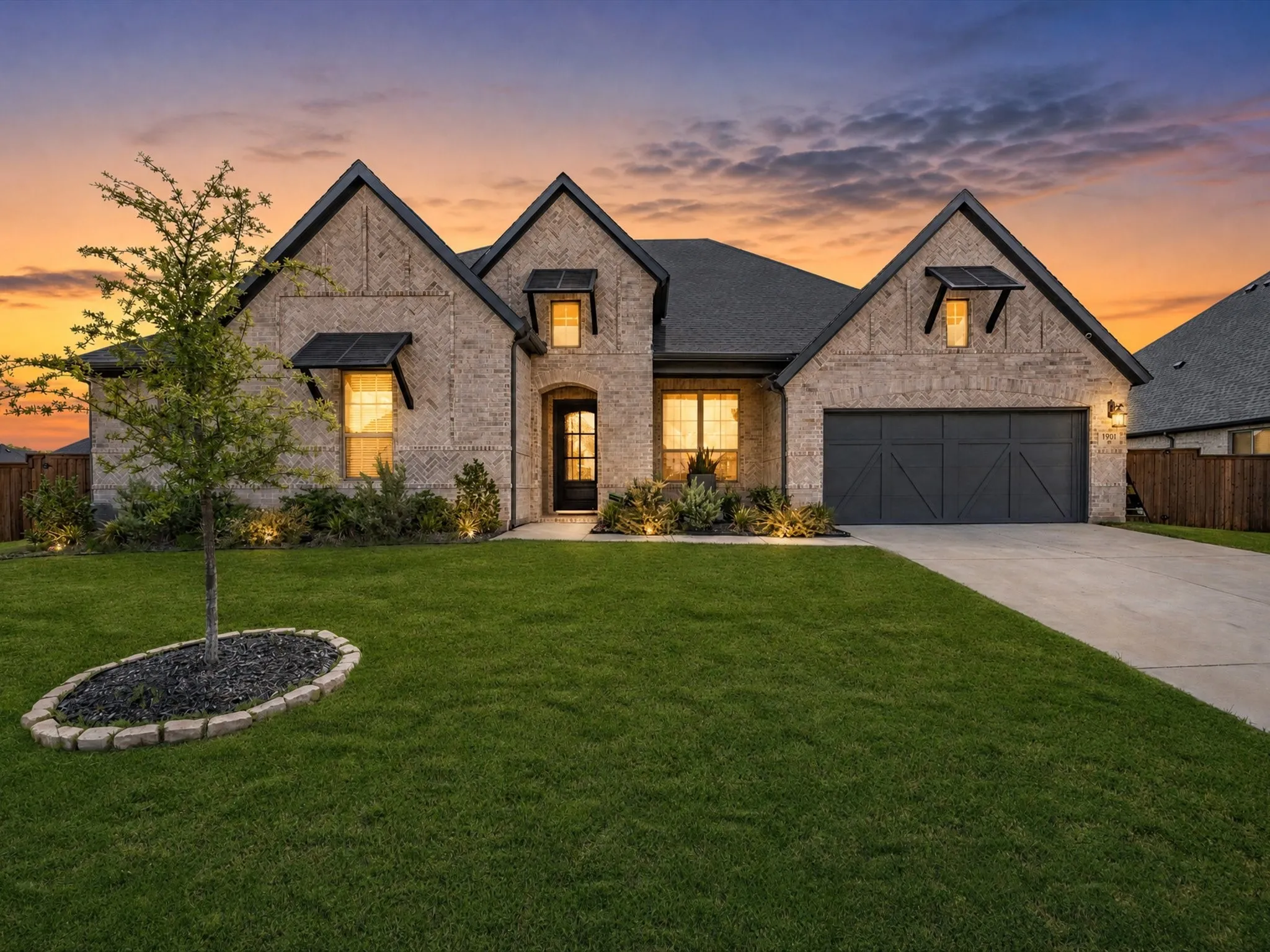 Stone veneer exterior with dark shingle roofing, prominent gables, and a two-car garage with a carriage-style door