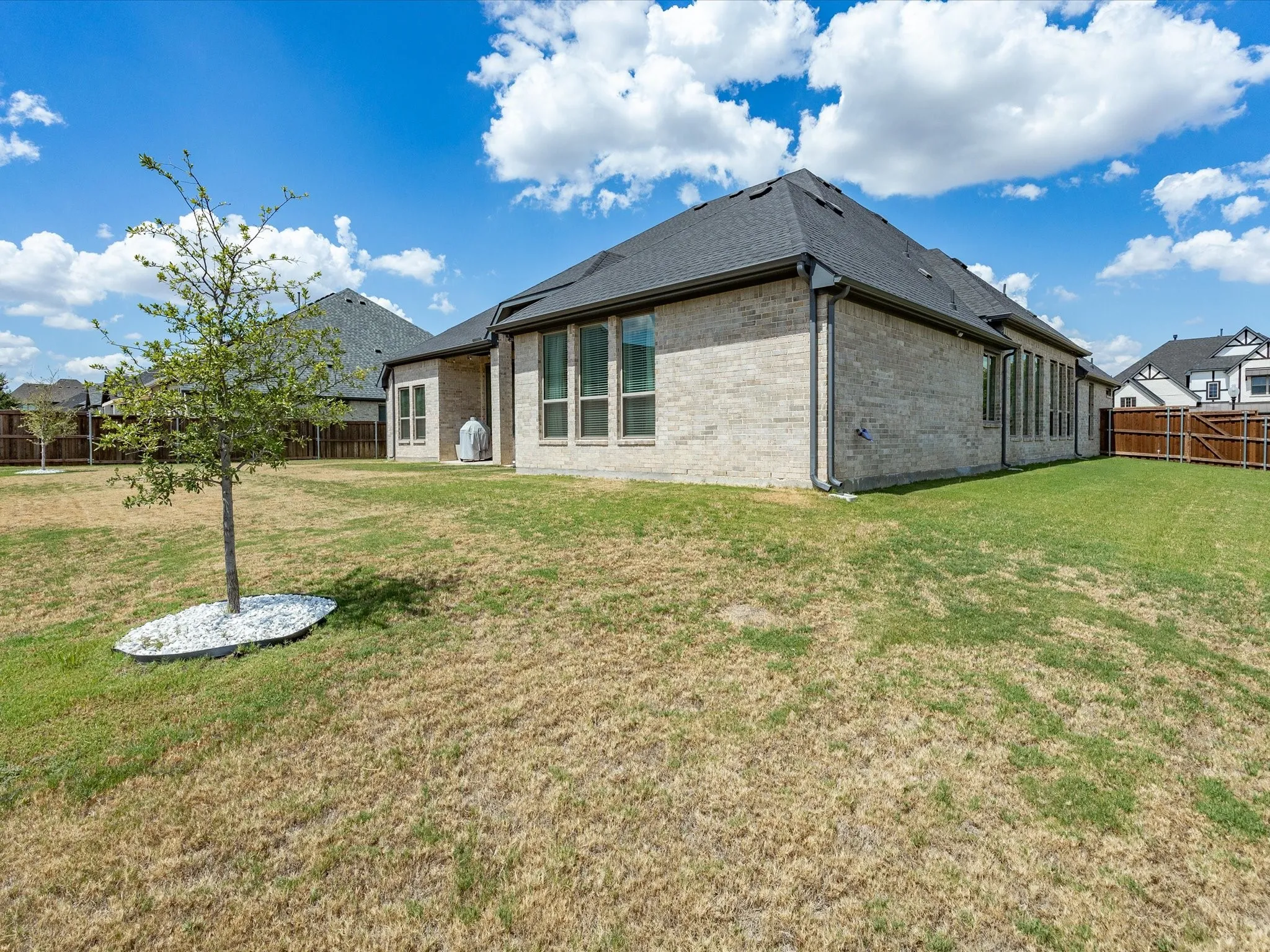 Exterior brick construction with a dark shingle roof and multiple large windows