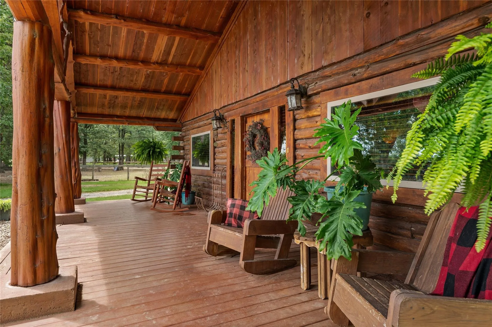 Expansive covered porch with exposed log beam construction and wood-finish flooring.