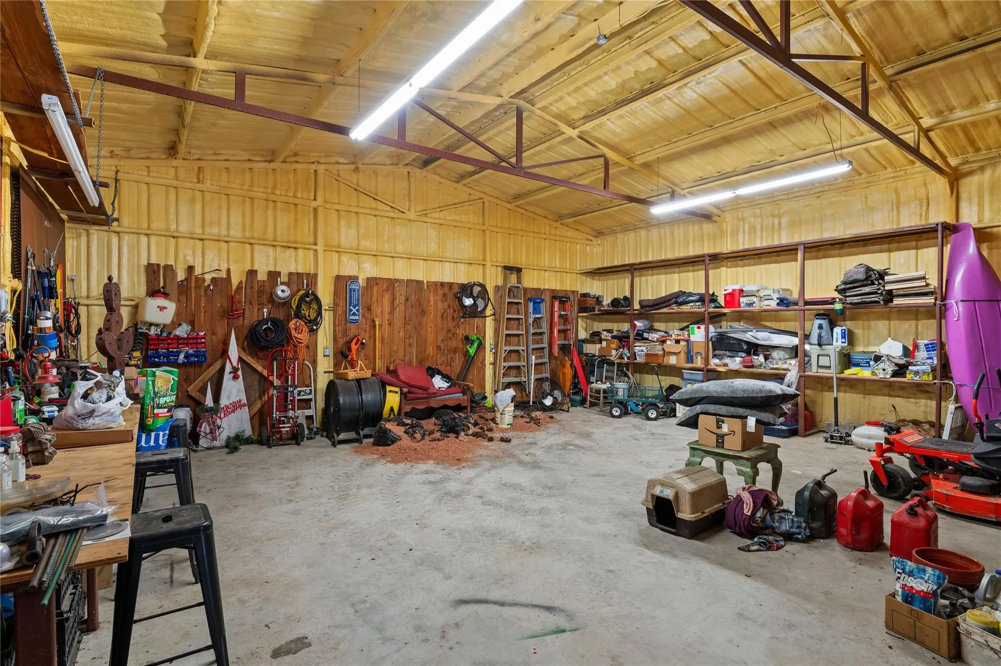 Spacious insulated garage with high ceilings, exposed metal beams, and concrete flooring.