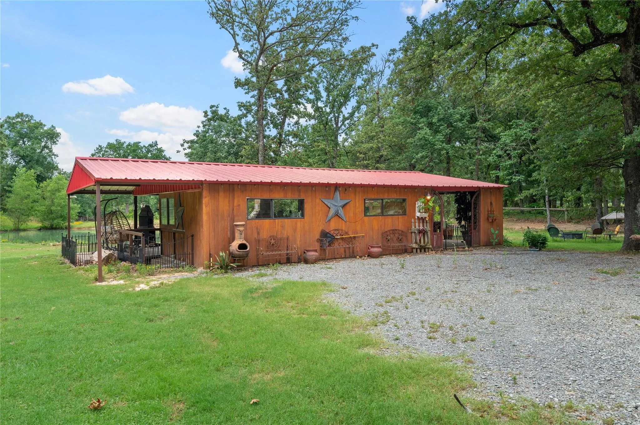 Outdoor living center situated on grassy grounds with mature trees and manicured​​‌​​​​‌​​‌‌​‌‌​​​‌‌​‌​‌​‌​​​‌​​ lawn.